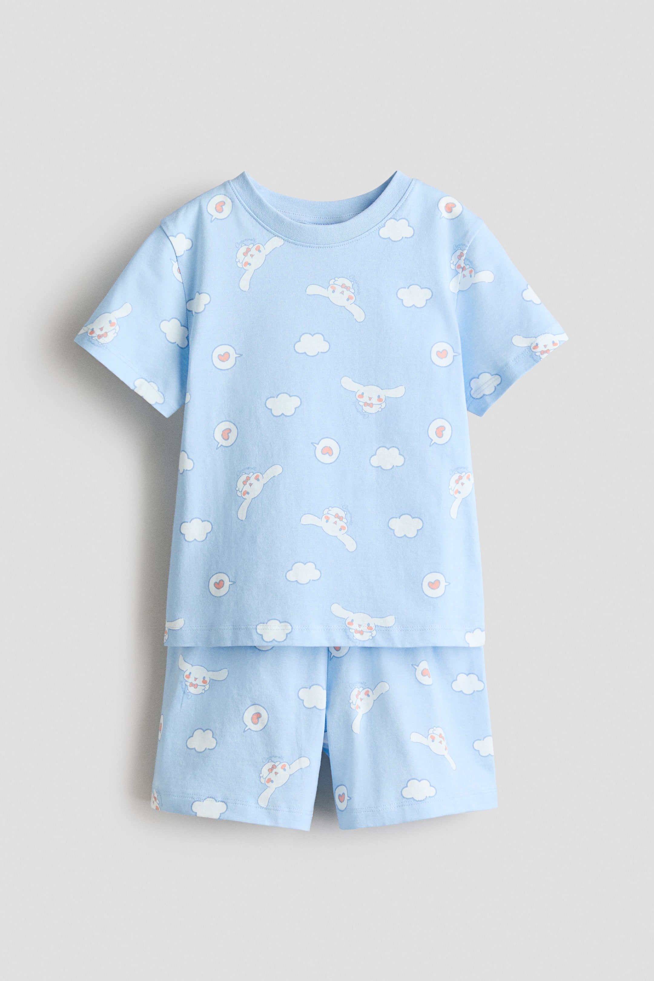 View larger image: Pyjamas set featuring a light blue tee and shorts showcased in front, both adorned with an all-over print of white cartoon characters, fluffy clouds, and small red hearts in speech bubbles. The tee highlights a round, ribbed neckline, short sleeves, and a straight-cut hem, while the shorts feature an elastic waistband.
