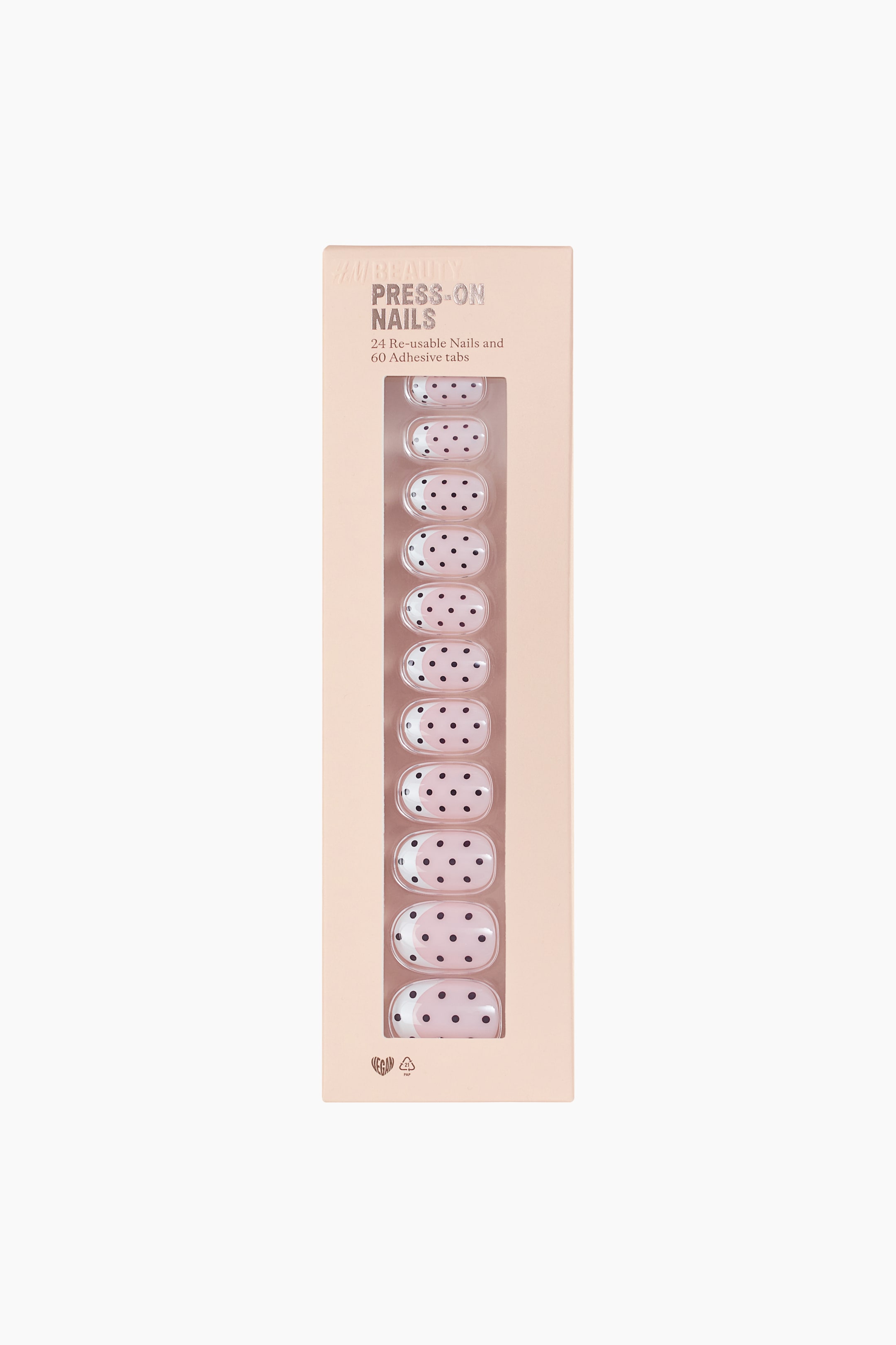 View larger image: A light peach-coloured rectangular box of press-on nails is displaying a front view, featuring "AMBEAUTY PRESS-ON NAILS" text and details about "24 Re-usable Nails and 60 Adhesive tabs". A clear window reveals oval-shaped nails that are light pink with black polka dots, with some nails at the bottom showcasing a white tip.