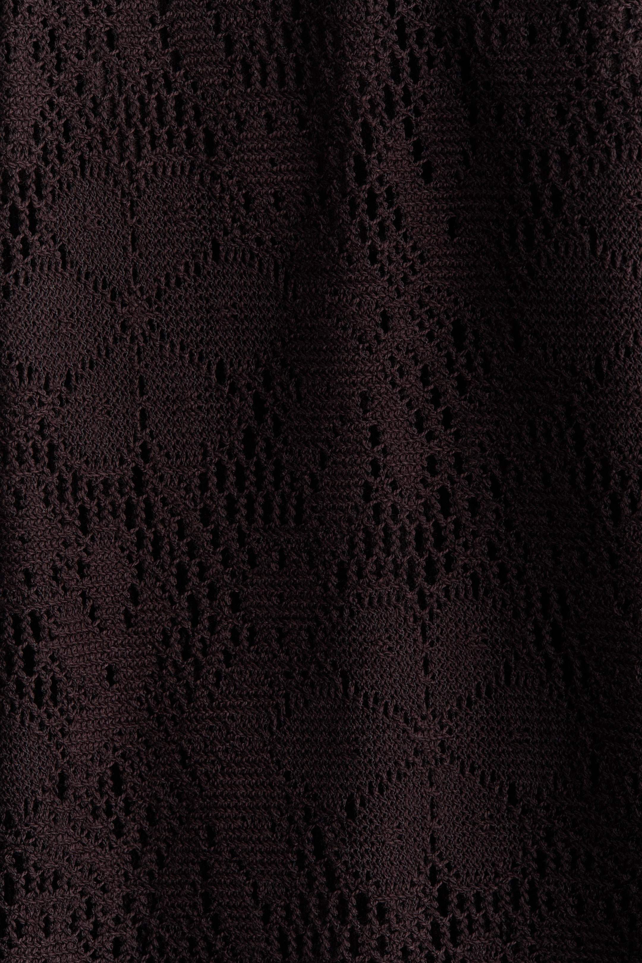 Agrandir l'image: Le pantalon est confectionné dans un tissu jersey à l'aspect crochet de couleur brun foncé. Il présente un motif de tricot ouvert et complexe sur toute sa surface.