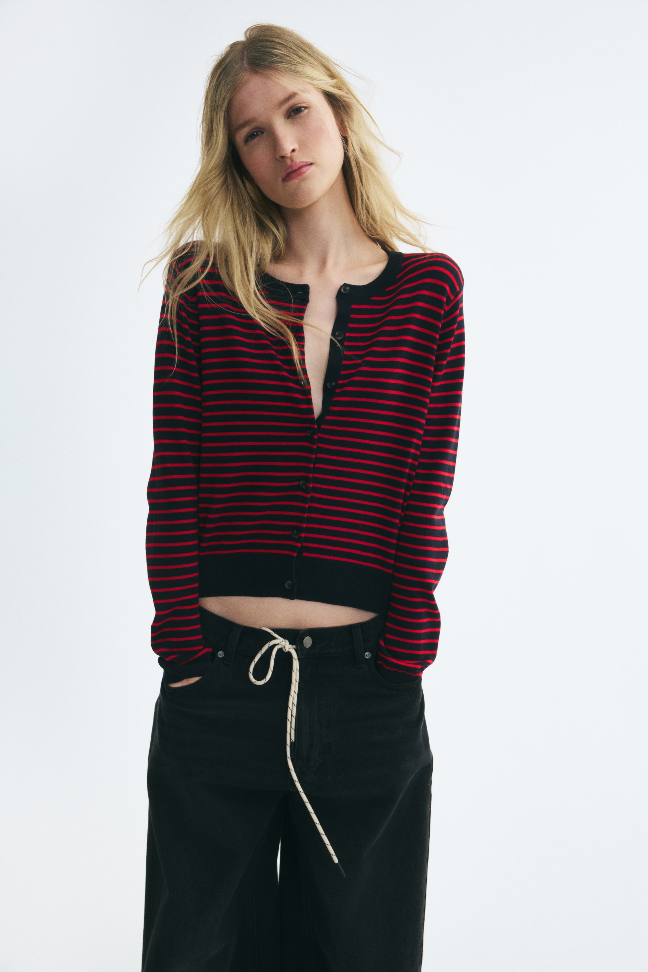 View larger image: A front-facing, long-sleeved cardigan in a red and black horizontally striped knit features a round, rib-trimmed neckline and black button closures down the front. The cardigan shows ribbed cuffs and a ribbed hem, styled partially unbuttoned at the chest.