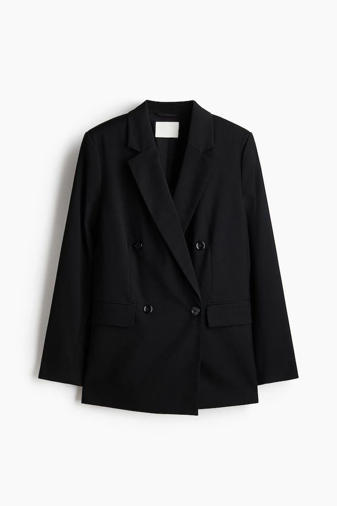 A black, slightly longer double-breasted blazer is facing front, featuring notch lapels and four black buttons at the front. It showcases structured shoulders, long sleeves, and two jetted front pockets with flaps. - 1