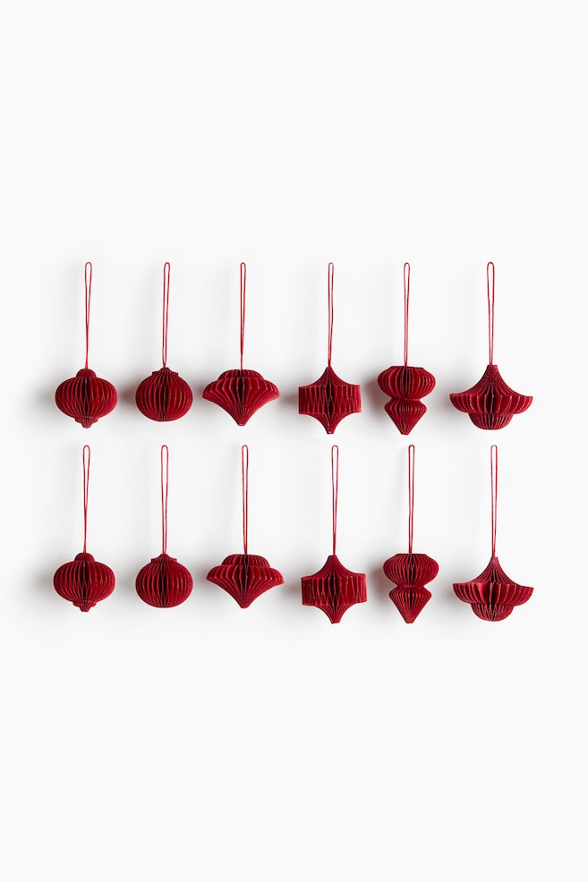 A set of twelve deep red paper ornaments featuring a pleated honeycomb structure is hanging in two rows of six, shown from the front. Each ornament is displaying a distinct geometric shape and is featuring a matching red string loop at the top. - 1