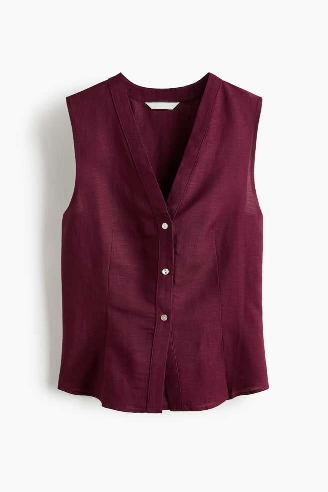 A deep burgundy sleeveless top is featuring a front view with a V-neckline and a full button-front closure. It is displaying four light-colored buttons down the center and subtle vertical shaping seams on the front. - 1