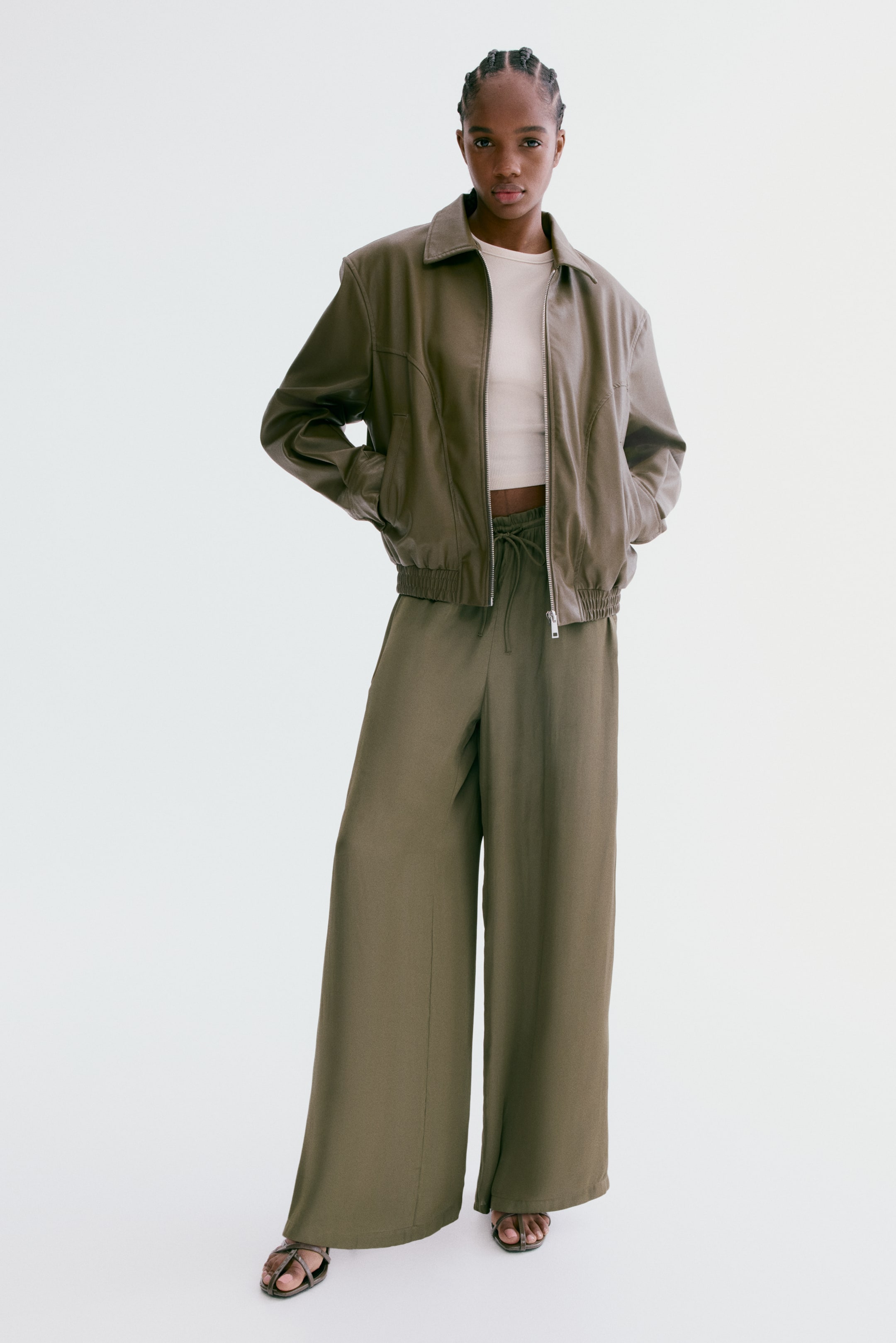 View larger image: The olive green wide-leg trousers feature a drawstring waist and a flowing silhouette, extending to the floor.