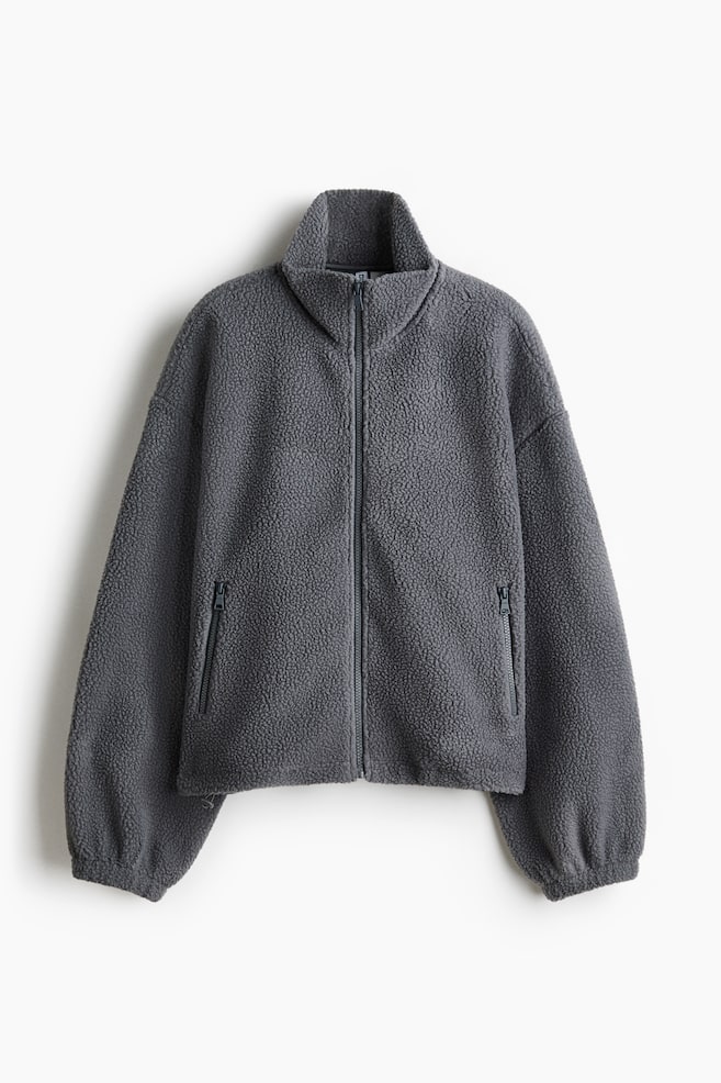A dark grey teddy fleece jacket is facing front, showcasing a full-length zipper closure and a standing collar. It is featuring two zippered pockets on the front, with the long sleeves ending in elasticated cuffs. - 1