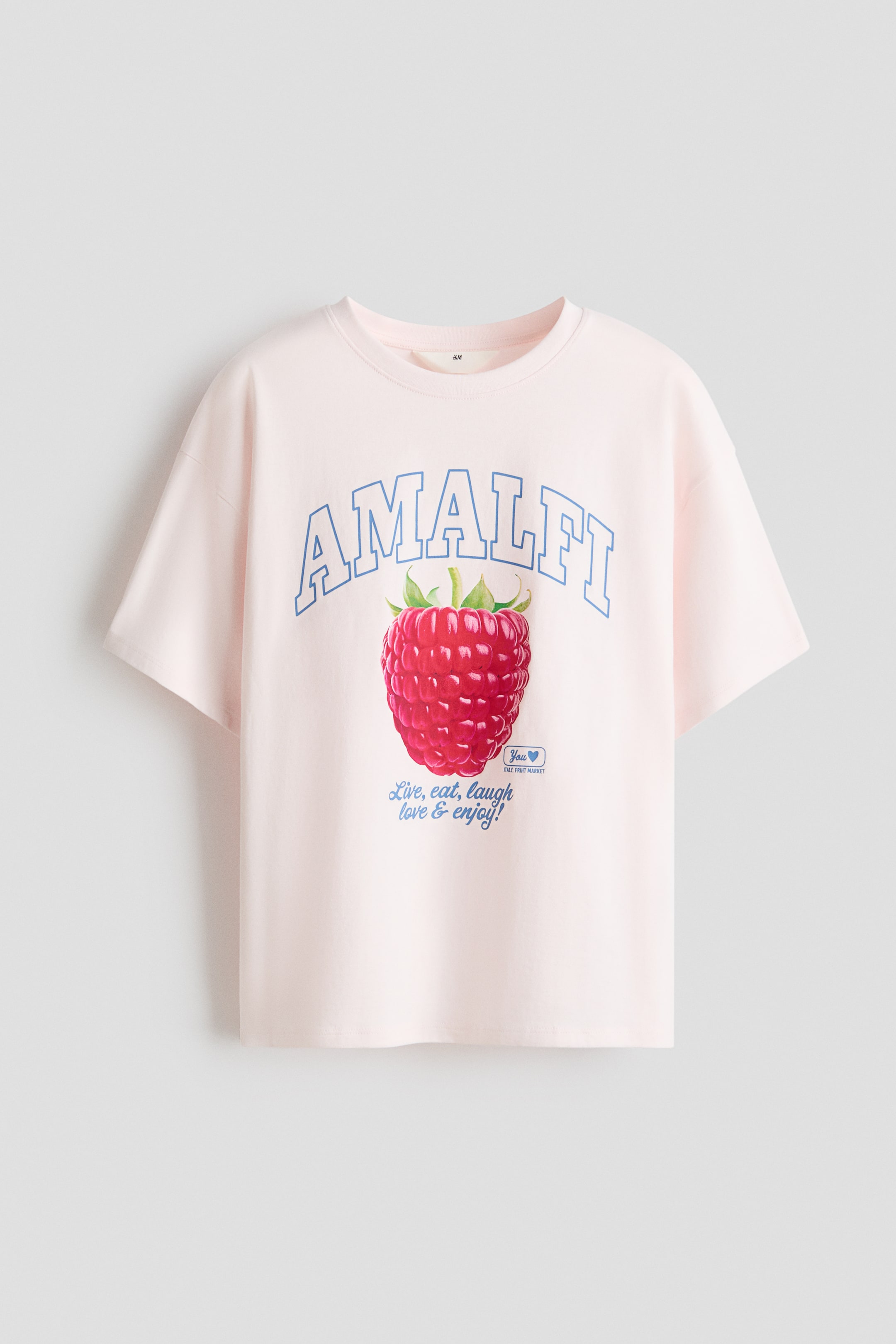 View larger image: An oversized, light-pink T-shirt in soft, printed cotton-jersey is presented from the front, featuring a round, rib-trimmed neckline, dropped shoulders and a straight-cut hem. The front print displays "AMALFI" in blue outline letters above a large red raspberry, with blue cursive text reading "Live, eat, laugh love & enjoy!" below.
