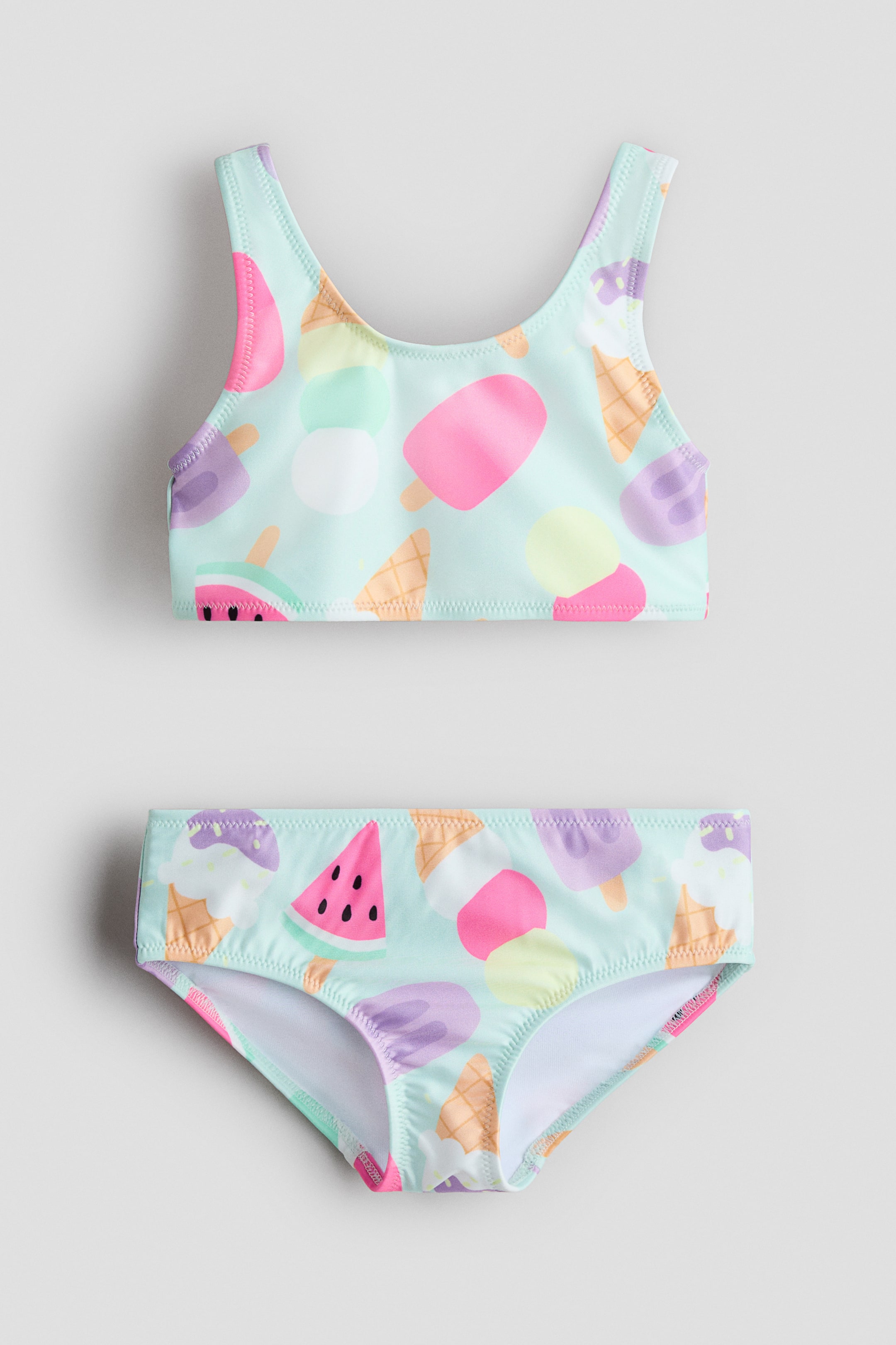 View larger image: "This printed bikini set includes a top and matching bottoms, both designed with a light blue backdrop adorned with a vibrant pattern of ice cream cones, popsicles, and watermelon slices. Each piece is fully lined and displayed in a front-facing manner."