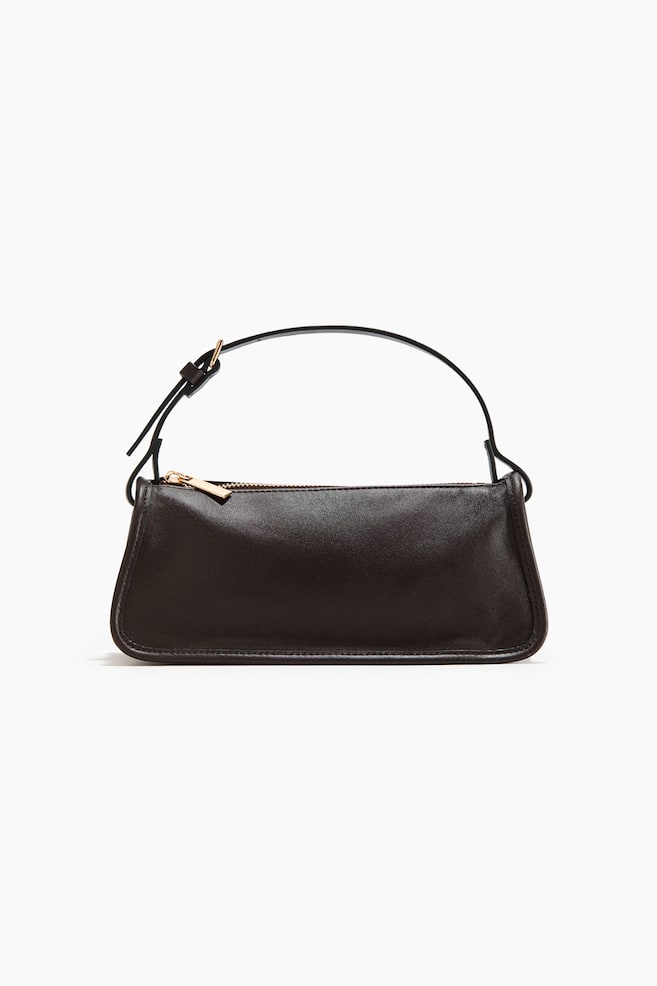 Un sac à bandoulière en cuir lisse marron foncé est présenté de face, arborant une forme rectangulaire avec des coins inférieurs arrondis. Une bandoulière étroite et réglable avec une boucle dorée est attachée, et une fermeture éclair dorée est visible sur le dessus. - 1