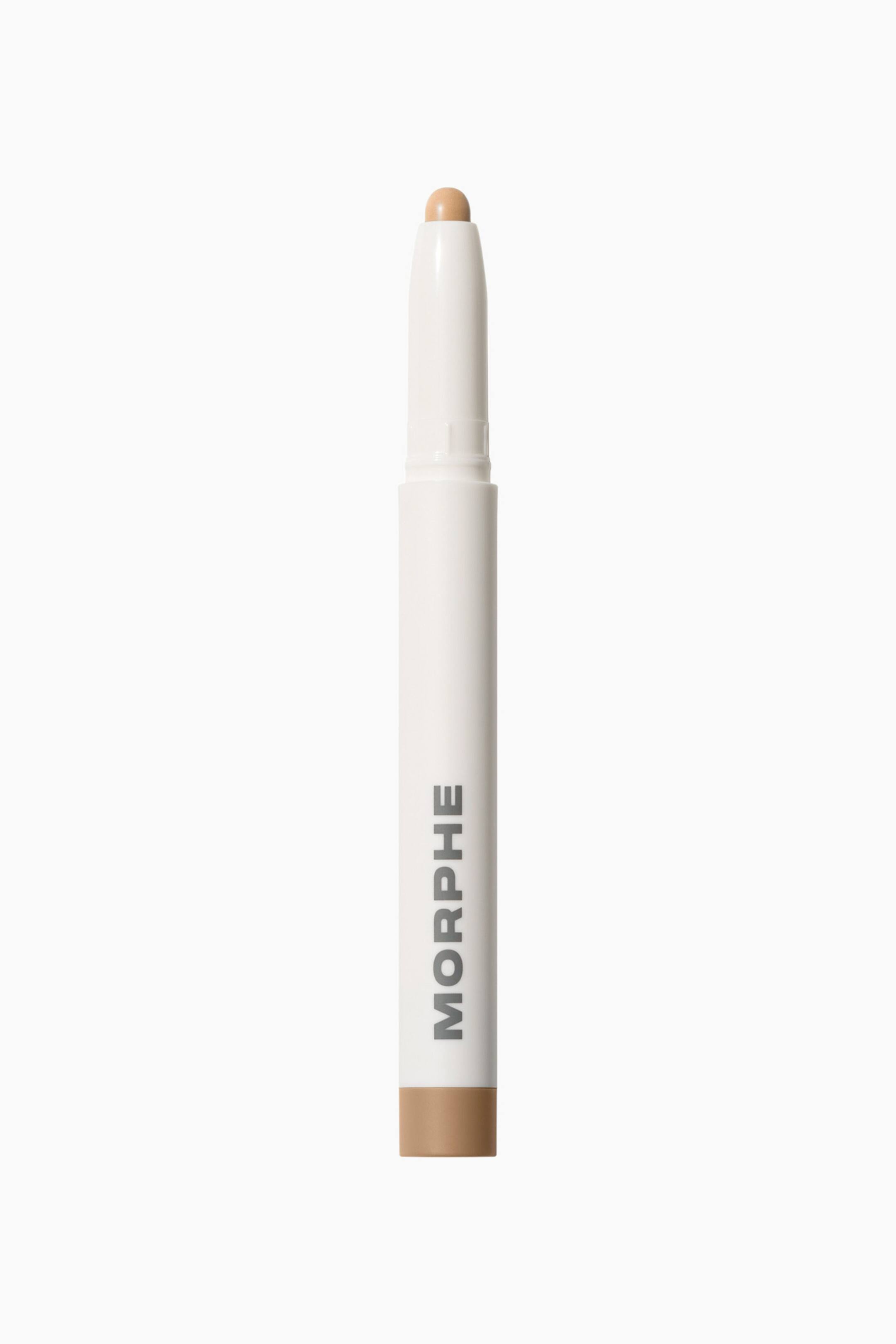 Visa större bild: En Morphe Shapelifter Micro Brightening Stick står vertikalt och visar upp sin smala, vita cylindriska behållare med ”MORPHE” tryckt lodrätt i grått. Den avlägsnade toppen visar en rundad, ljusbeige sminkspets som matchar det färgkodade bandet vid den nedre basen.