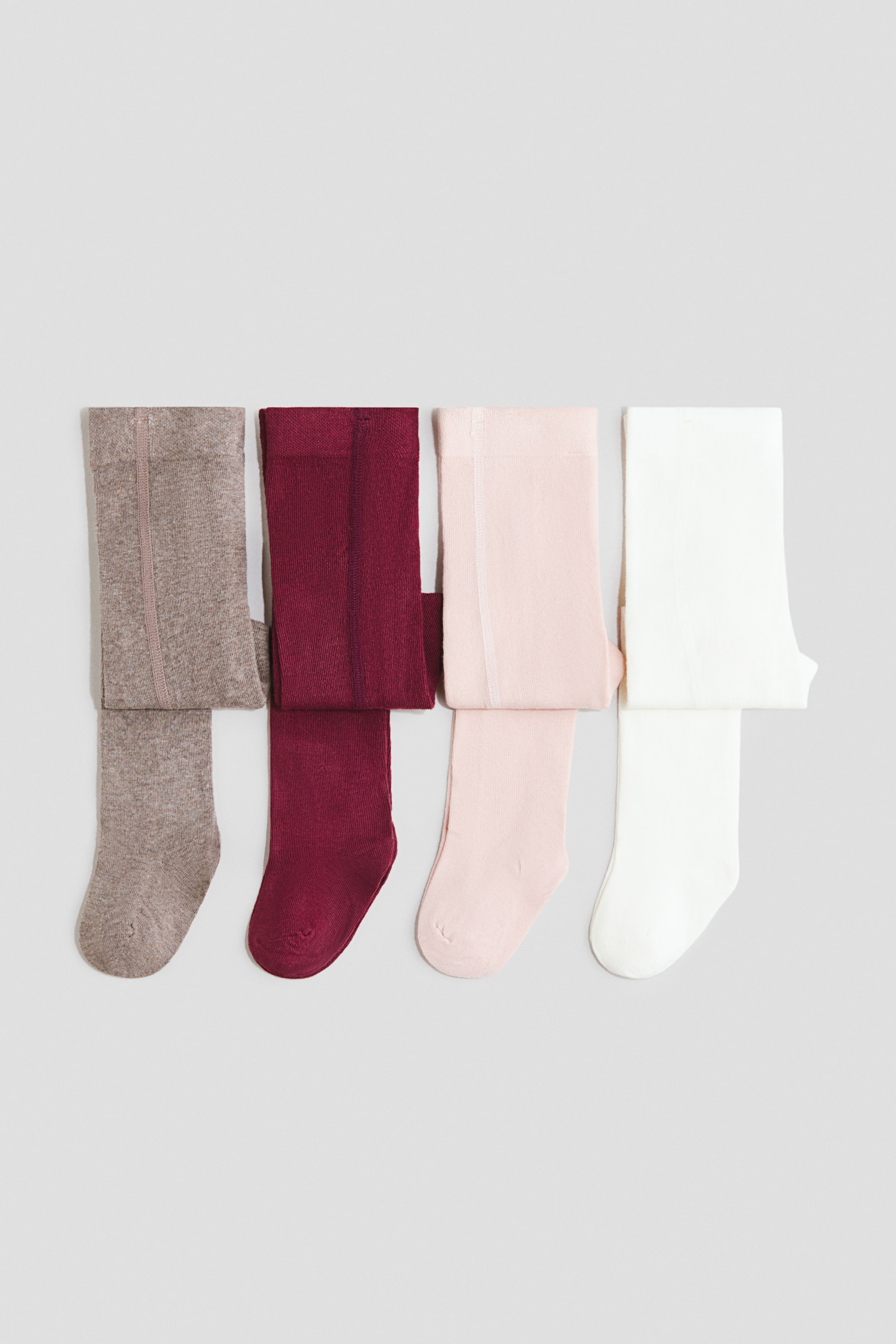 View larger image: Four pairs of tights are laid flat in a row, each folded to display the leg and foot. They feature a visible seam running down the back and come in brown, maroon, light pink, and off-white.