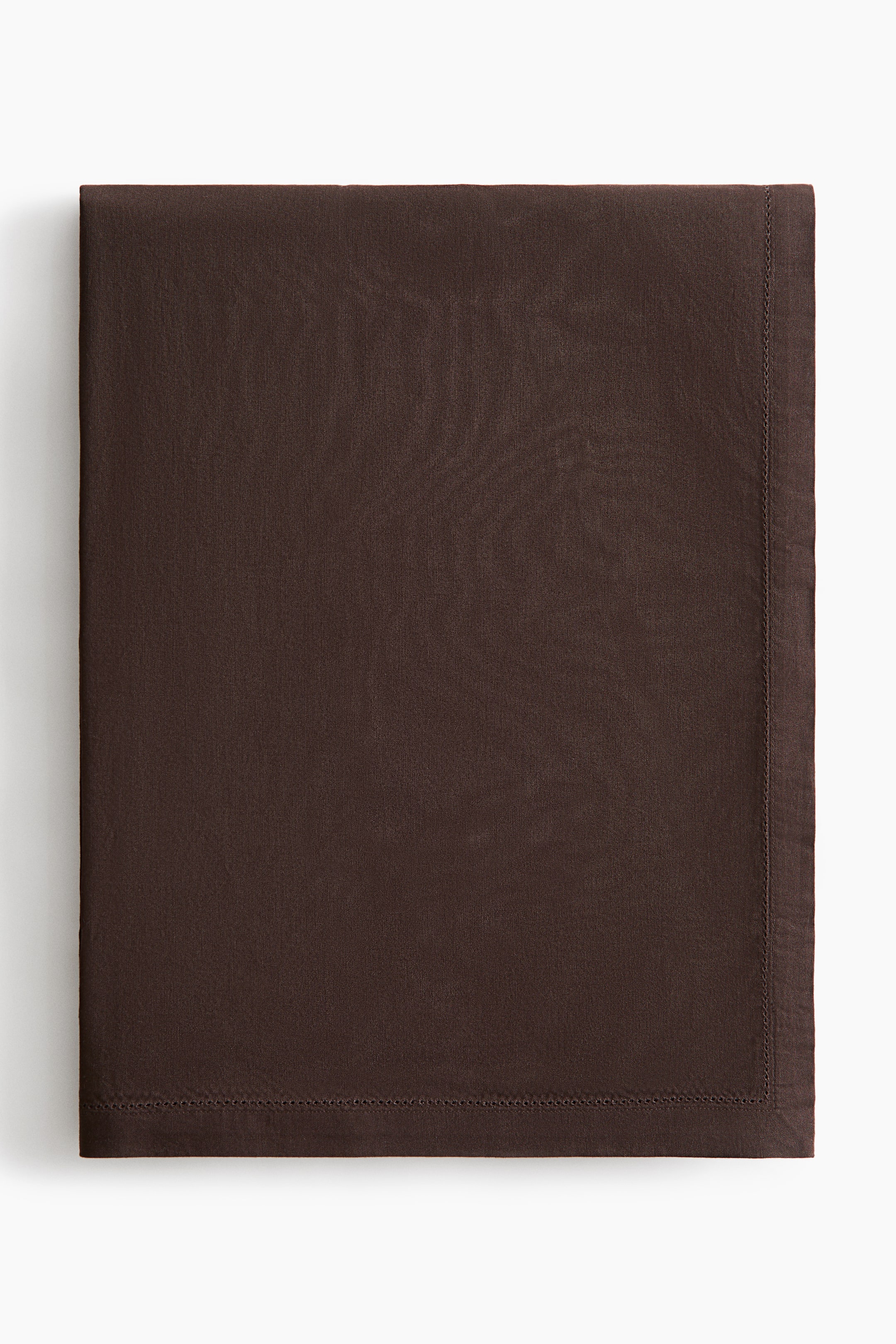 View larger image: A folded dark brown cotton tablecloth showcases its fine woven texture and a delicate hemstitch border running parallel to the wide hemmed edges. Presented in a flat-lay view, it highlights its clean rectangular shape and neat finish.