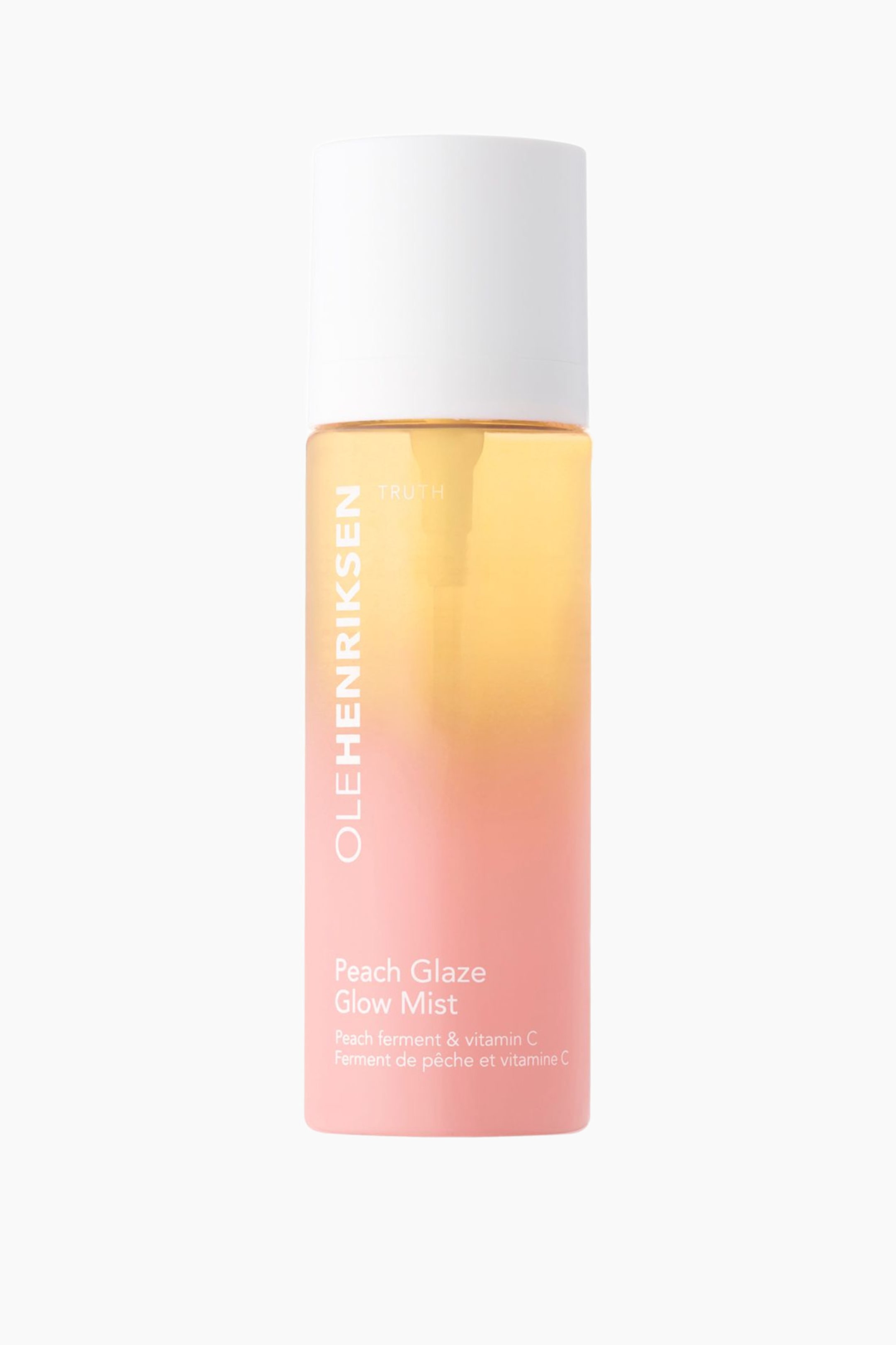 Se større billede: En flaske Ole Henriksen Peach Glaze Glow Mist står oprejst og vender fremad. Den har en hvid hætte og en gennemsigtig krop med en væske, der har en gradient, som går fra gul i toppen til pink i bunden. Teksten "OLEHENRIKSEN" er trykt lodret på venstre side, og "Peach Glaze Glow Mist" er trykt nær bunden.