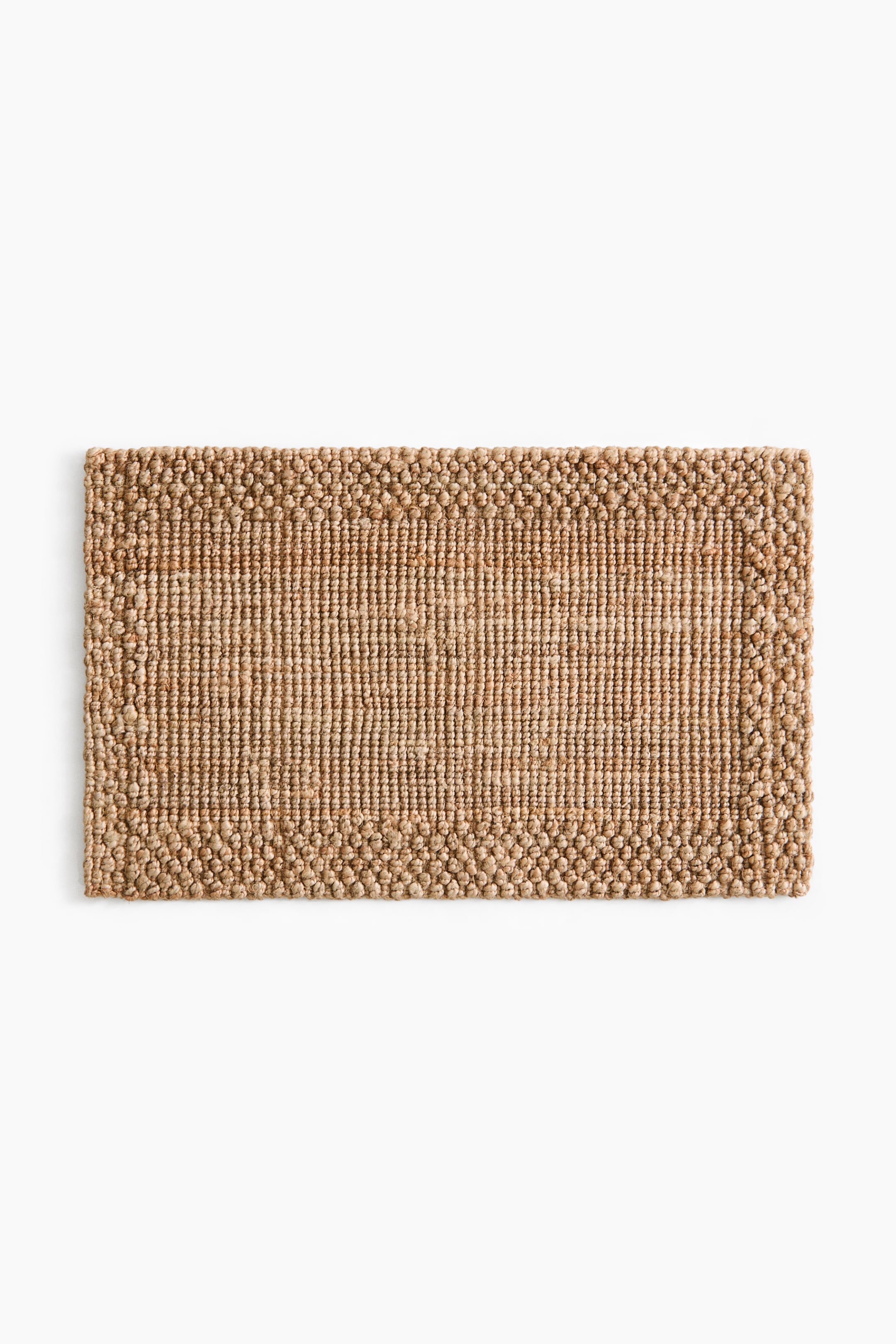 View larger image: A rectangular mat features a natural fibre construction, with a central area of tight, flat weave and a distinct, raised, irregularly looped border along all four sides.