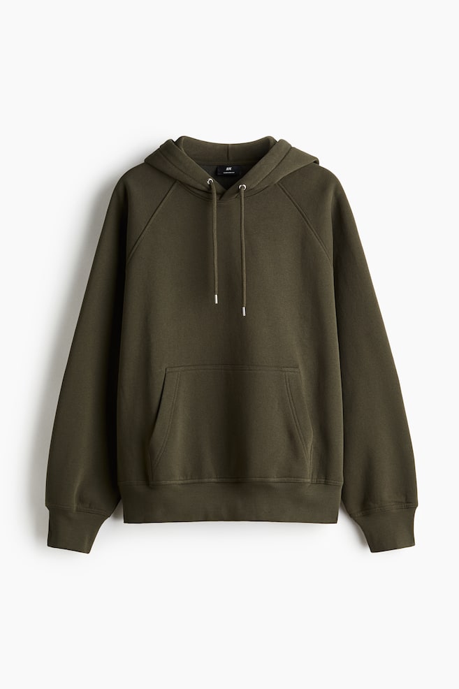 Ein dunkelgrüner Hoodie wird von vorne angezeigt, mit einer Kapuze und hellen Kordelzügen. Er ist mit Raglanärmeln, einer großen Kängurutasche vorne sowie gerippten Bündchen und Saum gestaltet. - 1