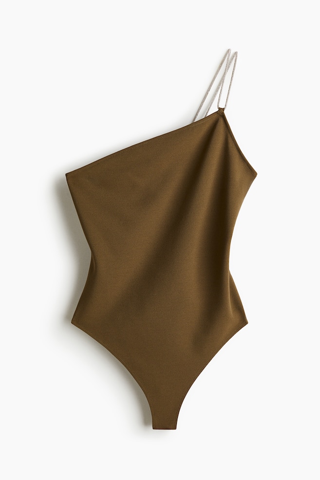 An olive green one-shoulder body is presenting its front view, featuring two thin rhinestone straps on the right shoulder and a strapless, straight neckline on the left. The fitted body is designed with a high-cut leg opening, forming a V-shape at the crotch. - 1