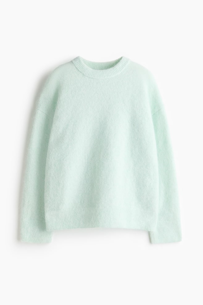 A light green fluffy jumper is presented front-facing, featuring a crew neck. It is designed with long sleeves, ribbed cuffs, and a ribbed hem. - 1