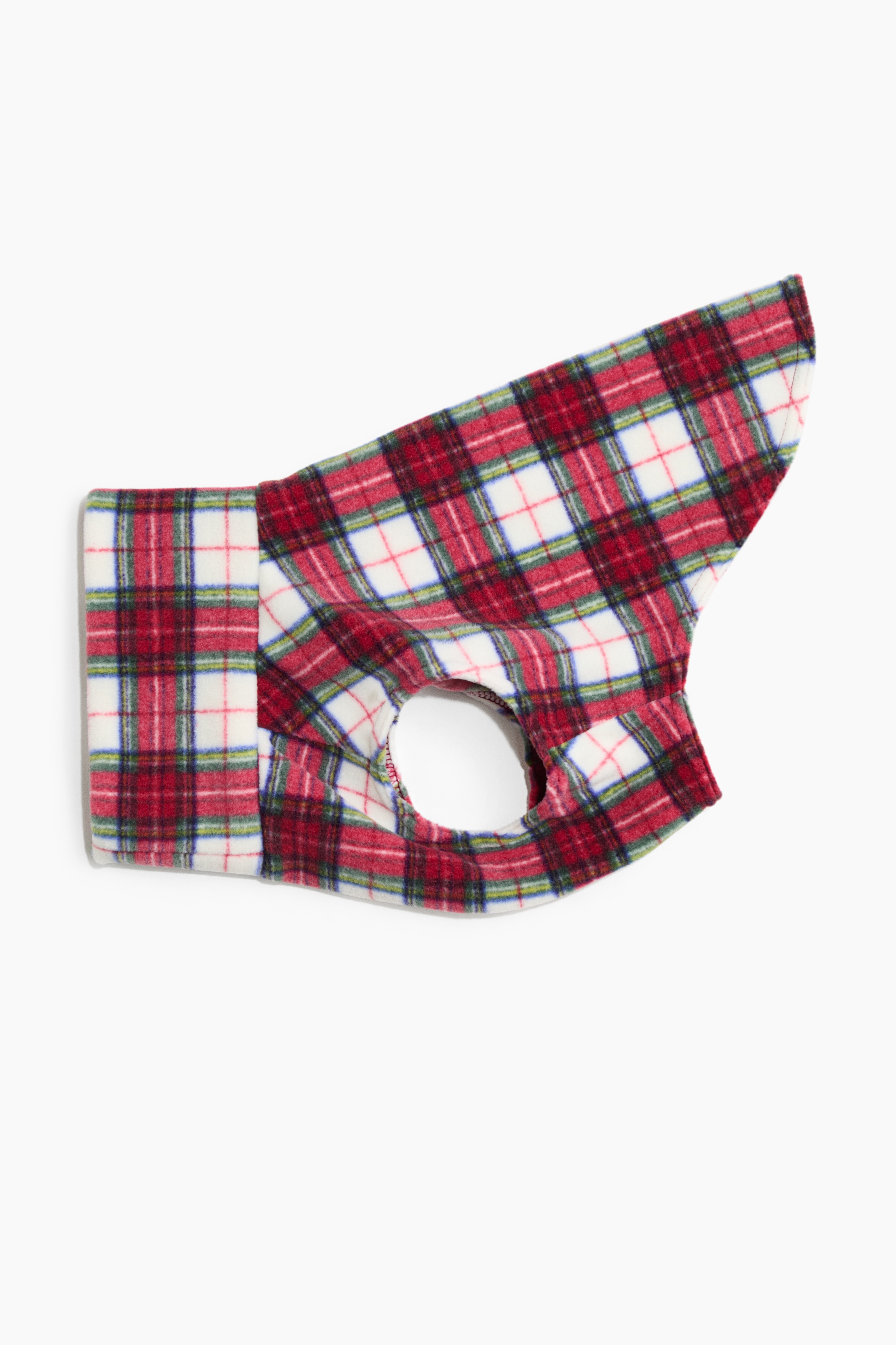 A dog shirt in a red, white and green plaid fleece pattern is being shown on a standing brown dog facing forward. The shirt features a high turtleneck collar and openings for the front legs, highlighting its soft texture and structured fit.