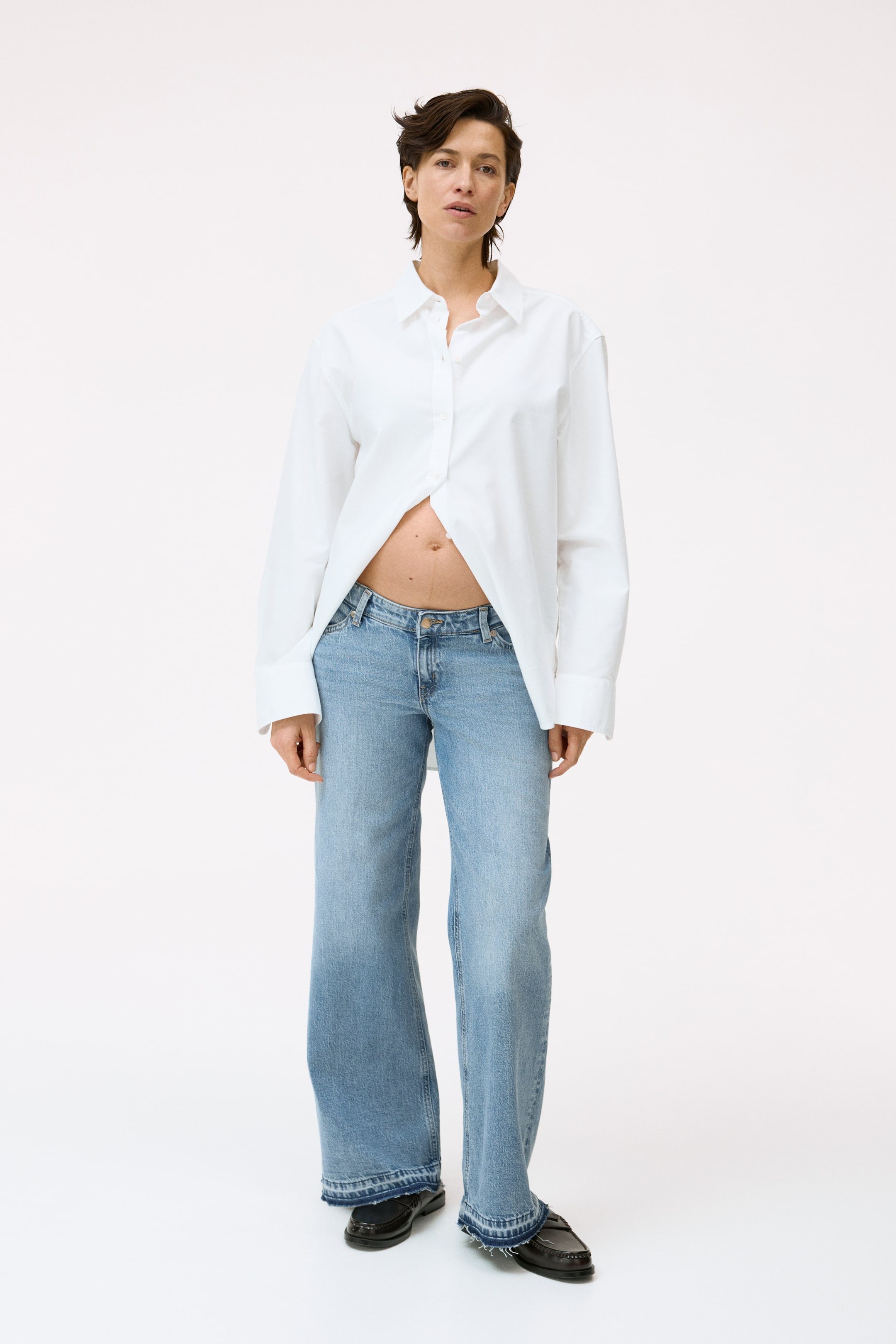 Grotere afbeelding bekijken: Licht gewassen denim jeans zijn naar voren gericht, met een lage taille, wijde pijpen en een rafelige zoom, zichtbare voorzakken en een knoop- en ritssluiting.