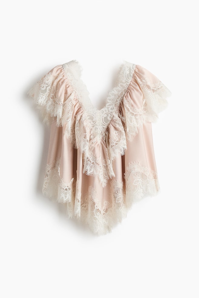 A sleeveless blouse in woven fabric is presented front-facing, detailed with lace trims throughout. It features a V-neckline at the front with a wide, gathered flounce trim continuing over the shoulders, creating a softly voluminous silhouette with gathers at the top and a V-shaped hem at the front. - 1