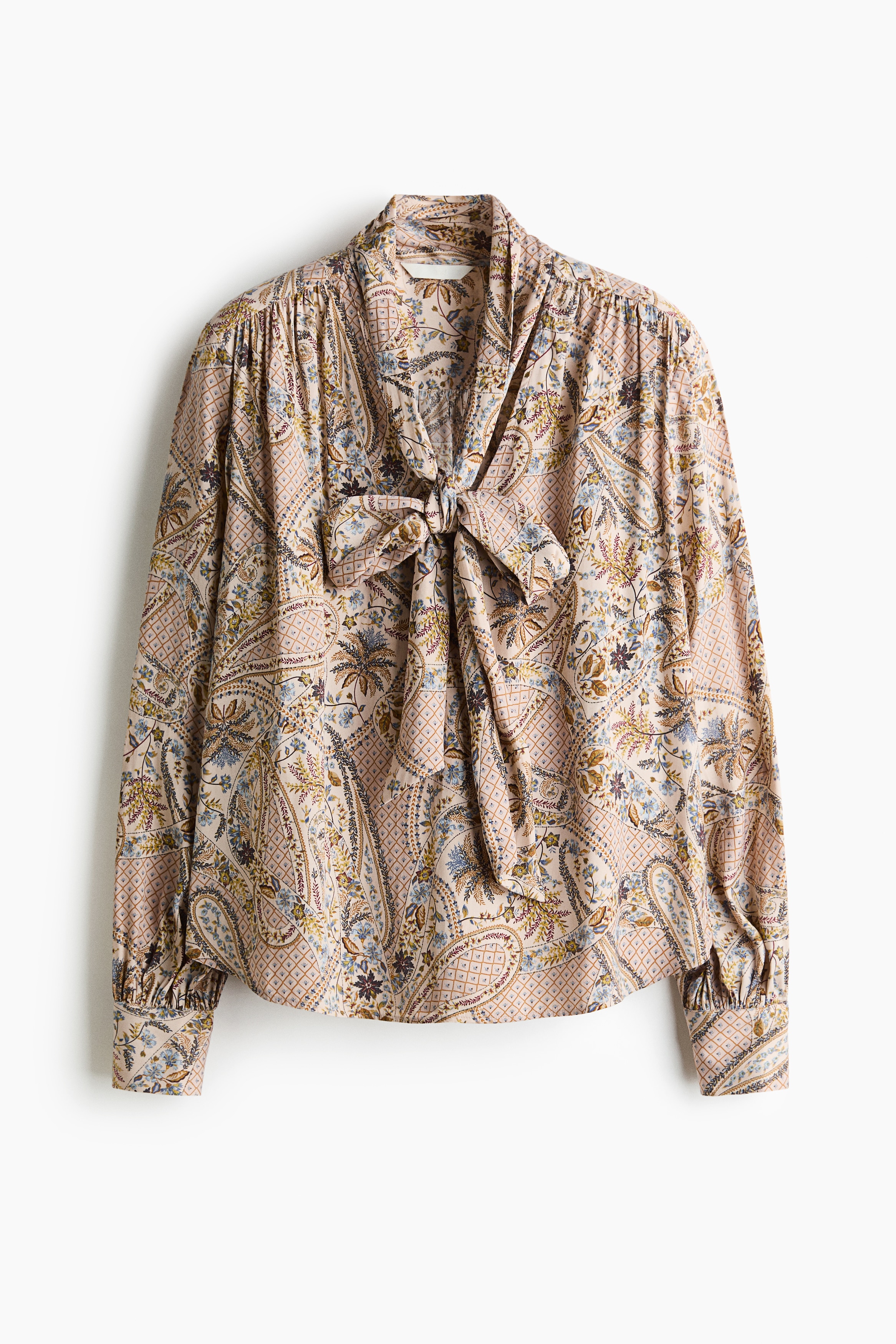 NgÆ°á»i máº«u Äang máº·c má»t chiáº¿c Ã¡o blouse dÃ¡ng rá»ng vá»i há»a tiáº¿t paisley nhiá»u mÃ u sáº¯c. Ão cÃ³ cá» chá»¯ V, cá» khÄn Äá»ng bá» quáº¥n quanh cá» vÃ  tay dÃ i nhÃºn bÃ¨o, ÄÆ°á»£c phá»i cÃ¹ng quáº§n jeans xanh.