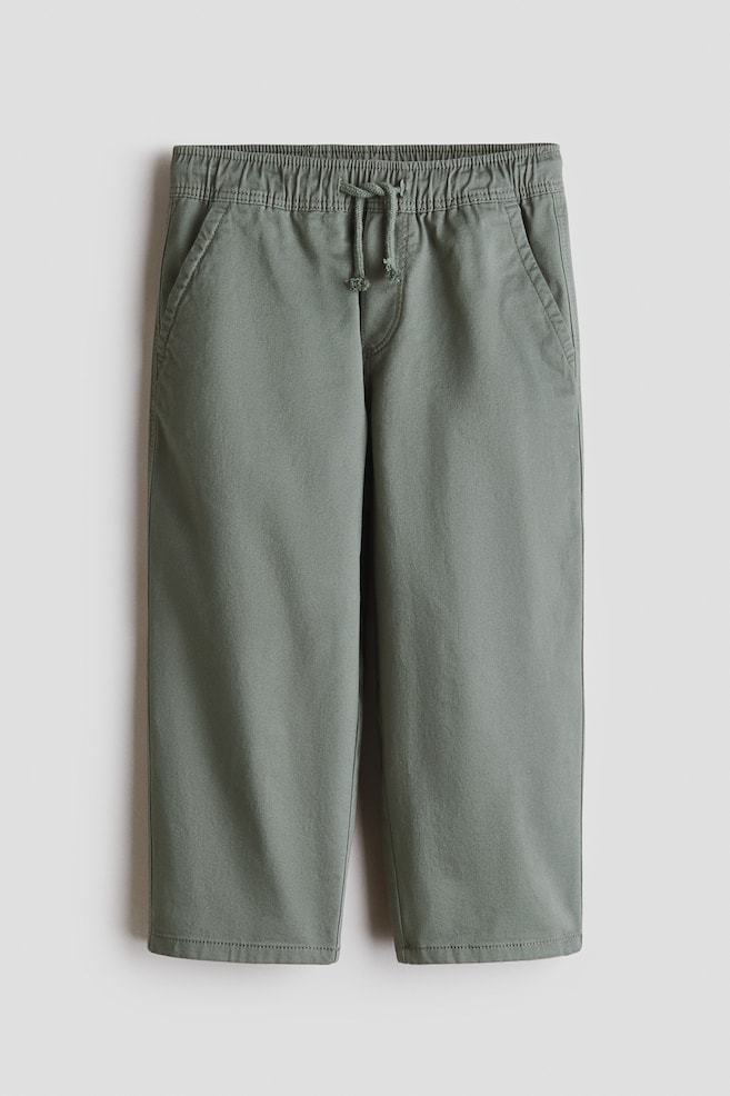 The sage green pants are featuring an elasticated waistband with a central drawstring and two side slash pockets. They are presenting a straight-leg cut, viewed from the front. - 1