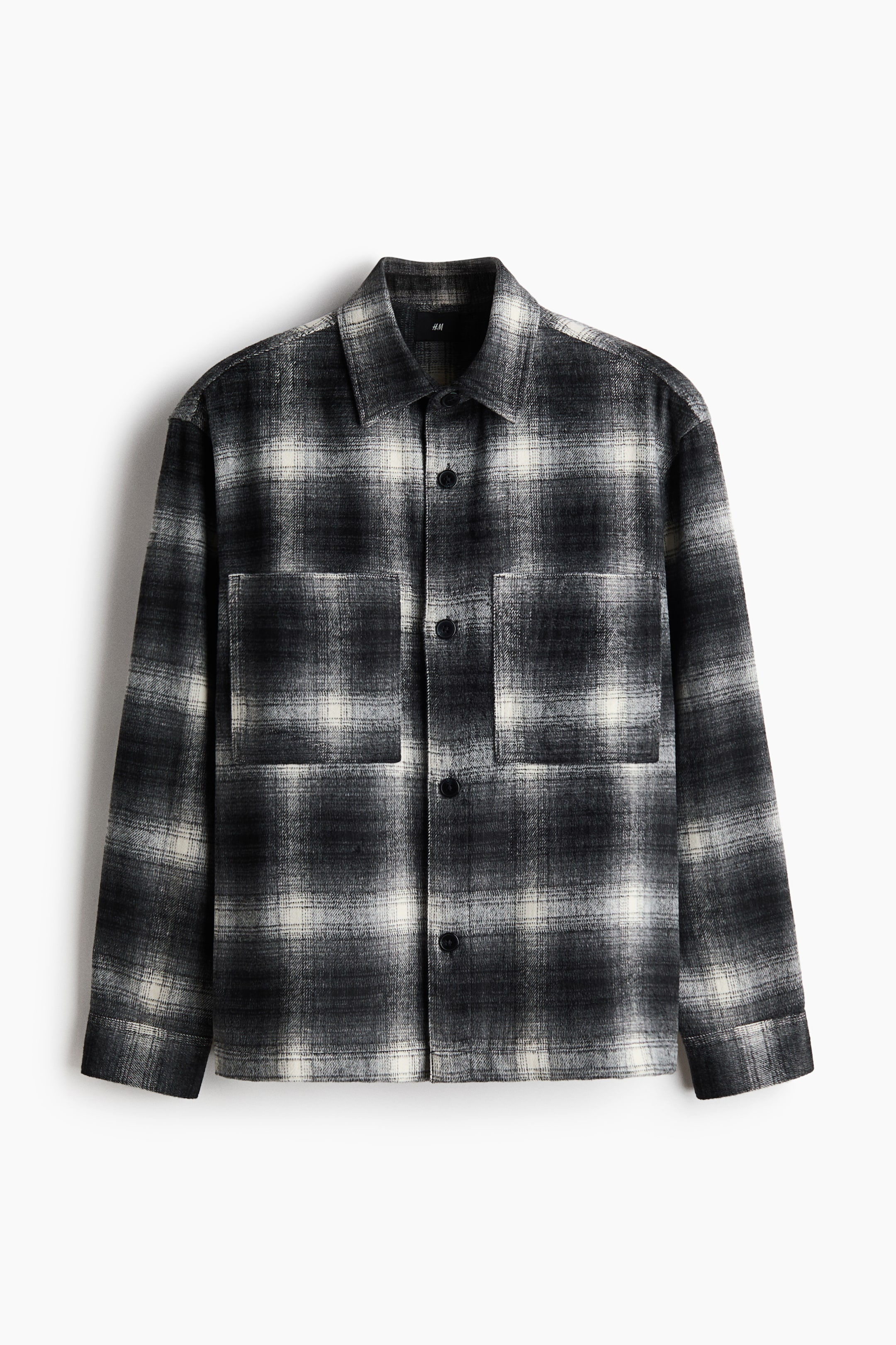 View larger image: A black and off-white plaid shirt jacket is shown from the front, featuring a classic pointed collar, a full button-front closure with dark buttons, and two flap chest patch pockets.