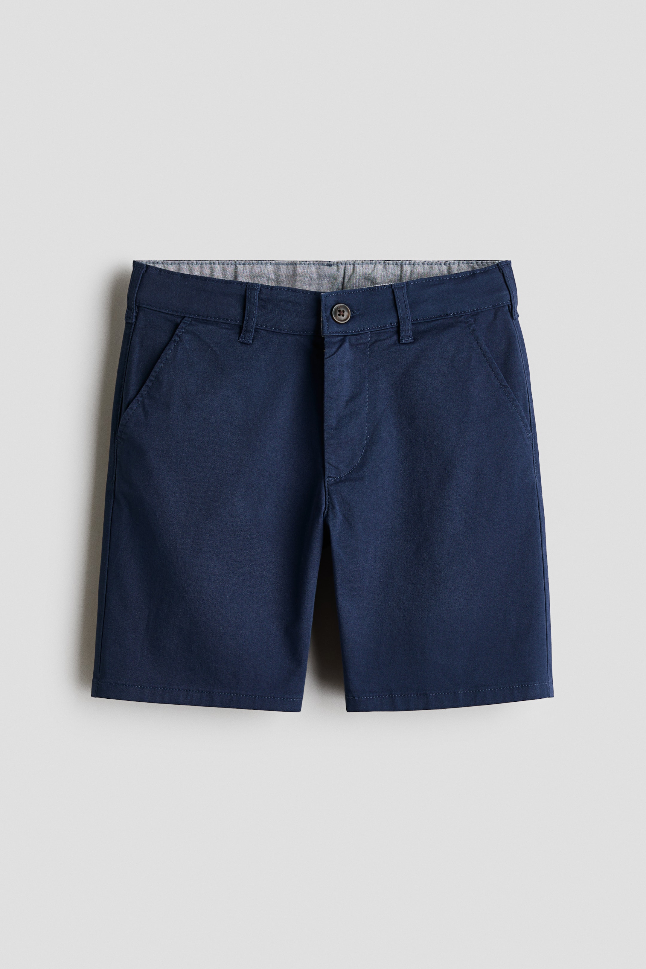Größeres Bild ansehen: Maßgeschneiderte Shorts aus einem dunkelblauen Twill-Stoff werden von vorne gezeigt. Sie verfügen über einen elastischen Bund, einen Knopfverschluss mit Reißverschluss und diagonale Seitentaschen.