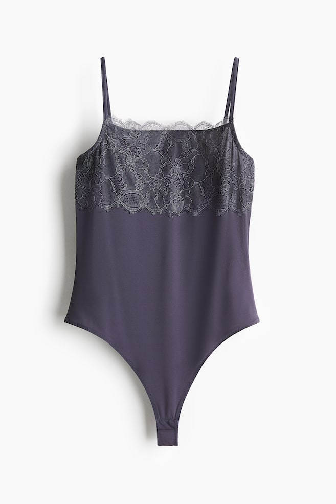 Front view of a dark gray bodysuit. It is featuring thin spaghetti straps and a floral lace overlay with a scalloped top edge across the bust. The smooth fabric body is tapering into a thong bottom. - 1