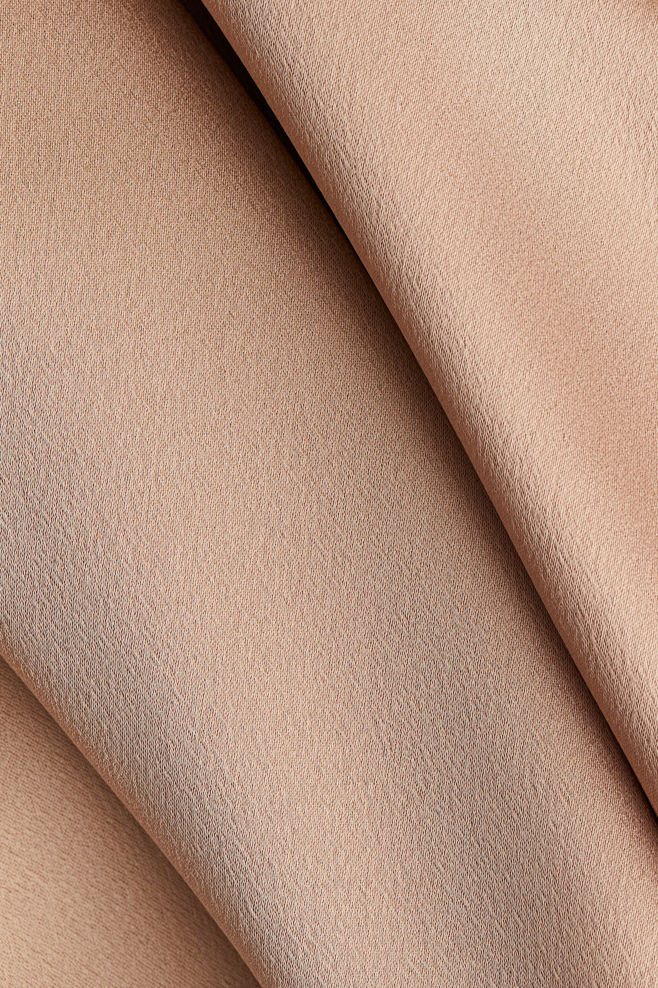 View larger image: A light brown, finely textured fabric is being draped, forming soft folds across the image.