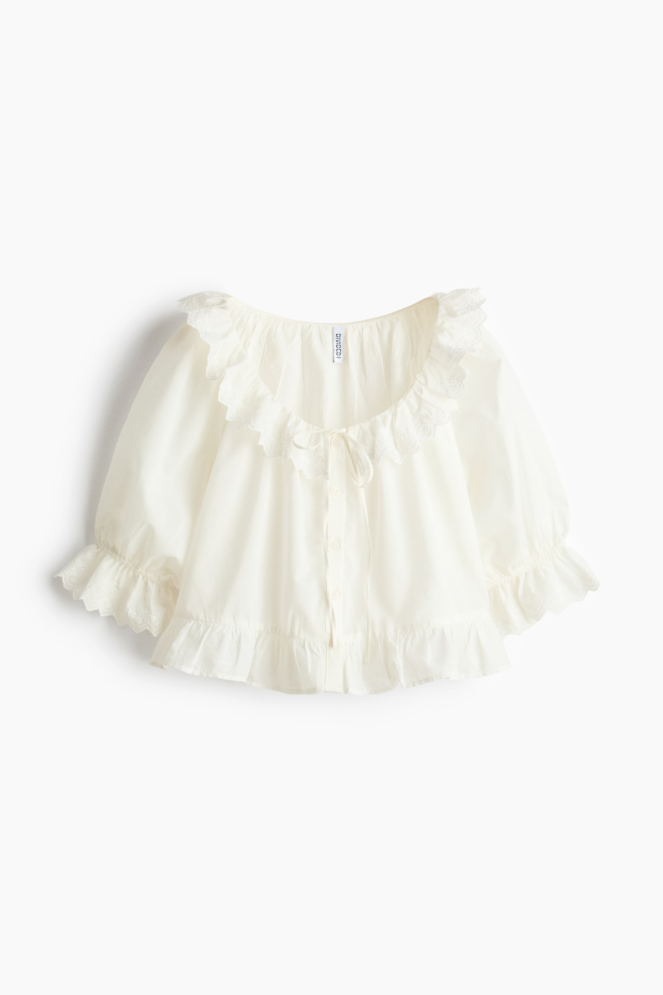 View larger image: A white blouse is showcased from the front, showcasing a broad ruffled neckline with eyelet detailing and a tie closure. It is crafted with voluminous elbow-length sleeves ending in elasticated ruffled cuffs, and a wide ruffled hem.