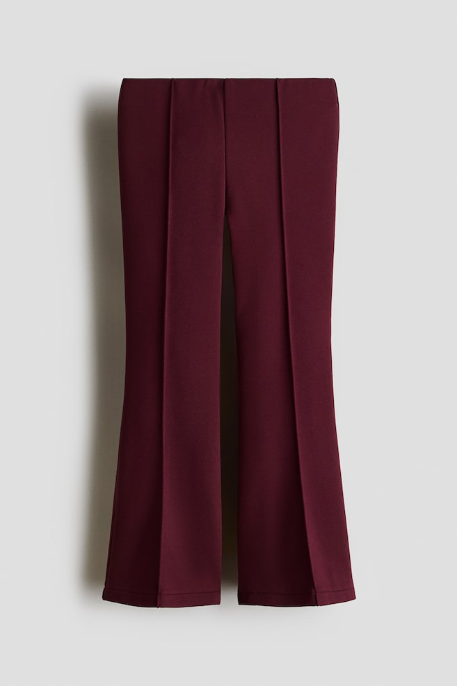 Dessa utsvÃ¤ngda leggings i vinrÃ¶d fÃ¤rg och kraftigt pontetyg har en slÃ¤t, dold midjeresÃ¥r och pressveck som Ã¤r fastsydda och lÃ¶per lÃ¤ngs mitten av varje ben. Benen vidgas utÃ¥t mot fÃ¥llen fÃ¶r att skapa en strukturerad silhuett i framifrÃ¥nvy. - 1