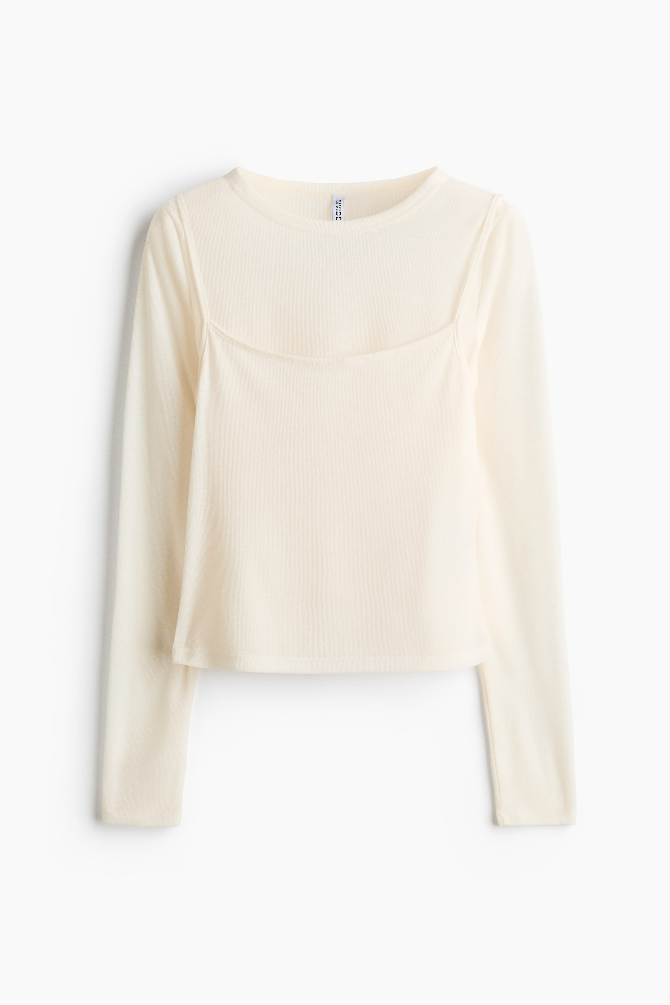 View larger image: A cream-colored long-sleeve top showcases a unique design, featuring a crew-neck base layer with a square-neck panel and thin straps. It displays a subtle ribbed texture throughout and has a cropped hem.