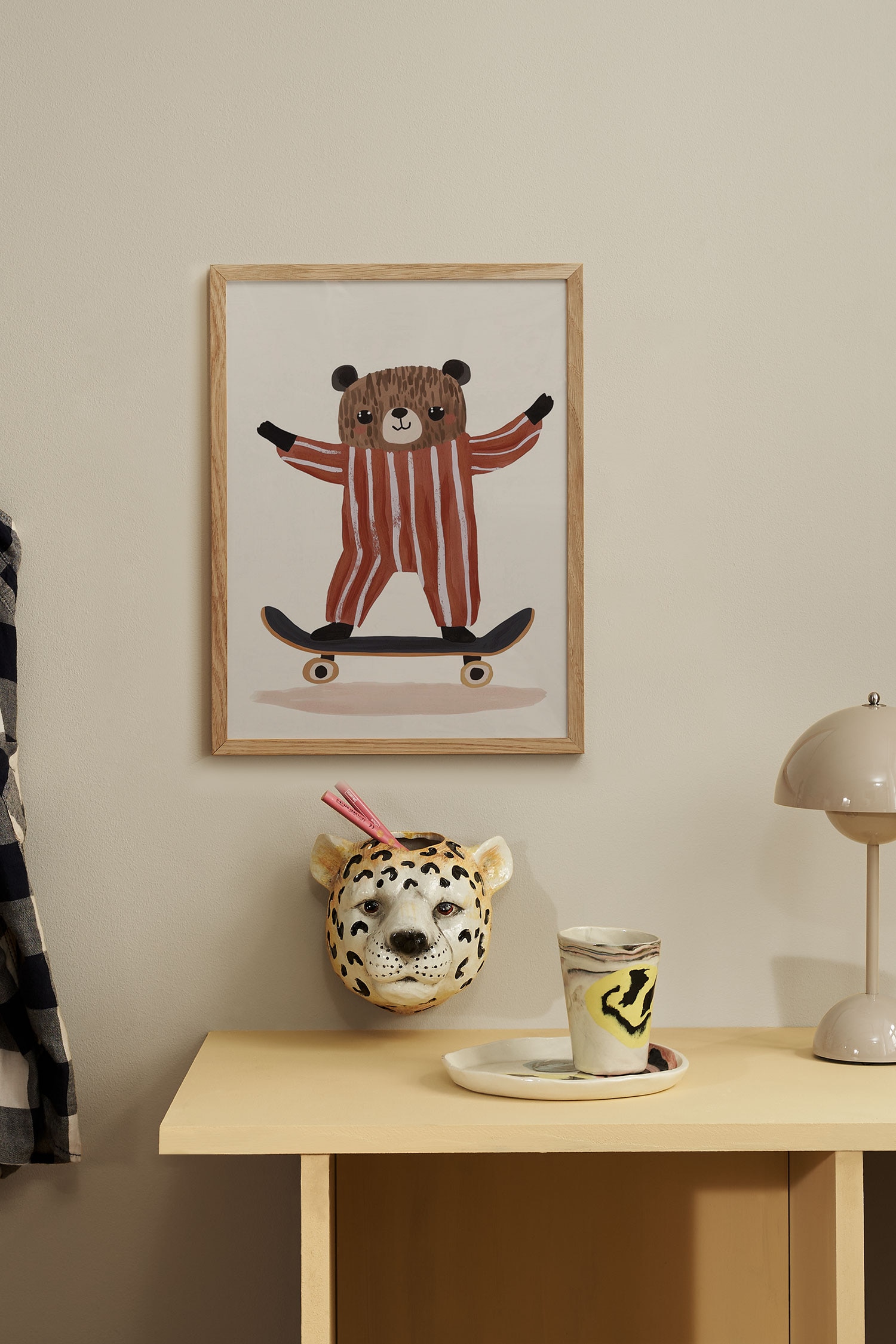 Een kunstprint toont een geschilderde illustratie van een gestileerde bruine beer die een rood-wit gestreepte jumpsuit draagt terwijl hij op een skateboard rijdt. De beer staat met zijn armen uitgestrekt tegen een effen, licht crÃ¨mekleurige achtergrond.