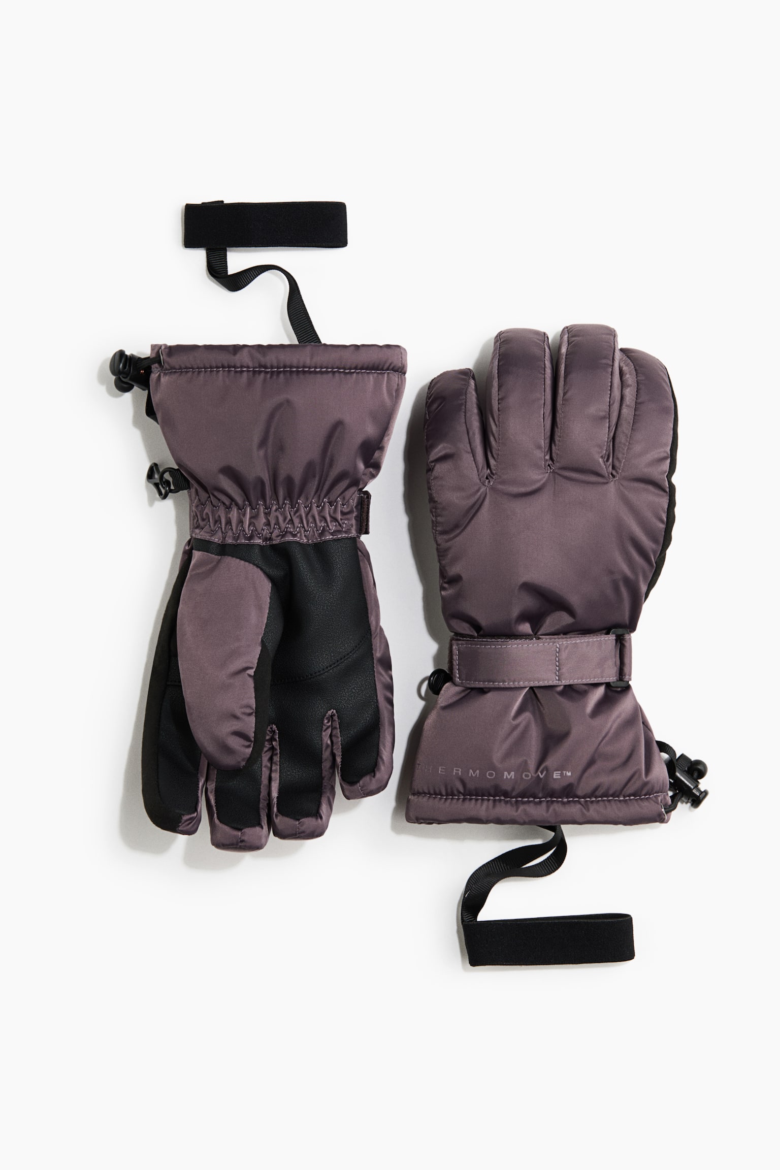 Een paar gewatteerde winterhandschoenen in stoffig paars wordt getoond, waarbij de ene handschoen van voren is afgebeeld om de getextureerde zwarte grip in de handpalm te laten zien en de andere de gewatteerde achterzijde toont. De handschoenen zijn voorzien van verstelbare polsbanden met klittenband, elastische polsen, koordsluitingen aan de manchetten en zwarte elastische polslussen.