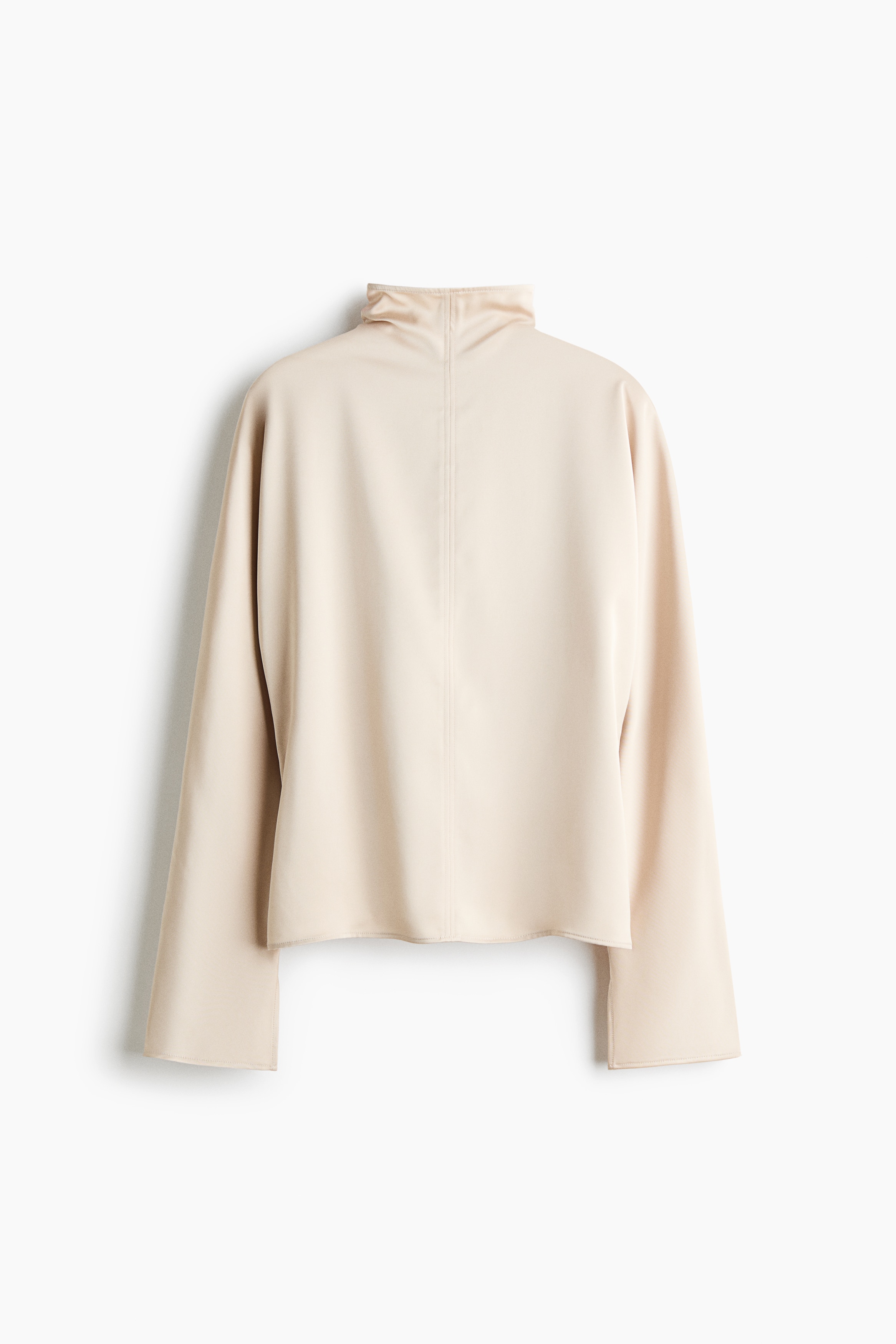 The pale pink satin top is shown from the front, featuring a mock neck and relaxed long sleeves. It is paired with a black sheer lace midi skirt, showcasing an intricate floral pattern and a scalloped hem.