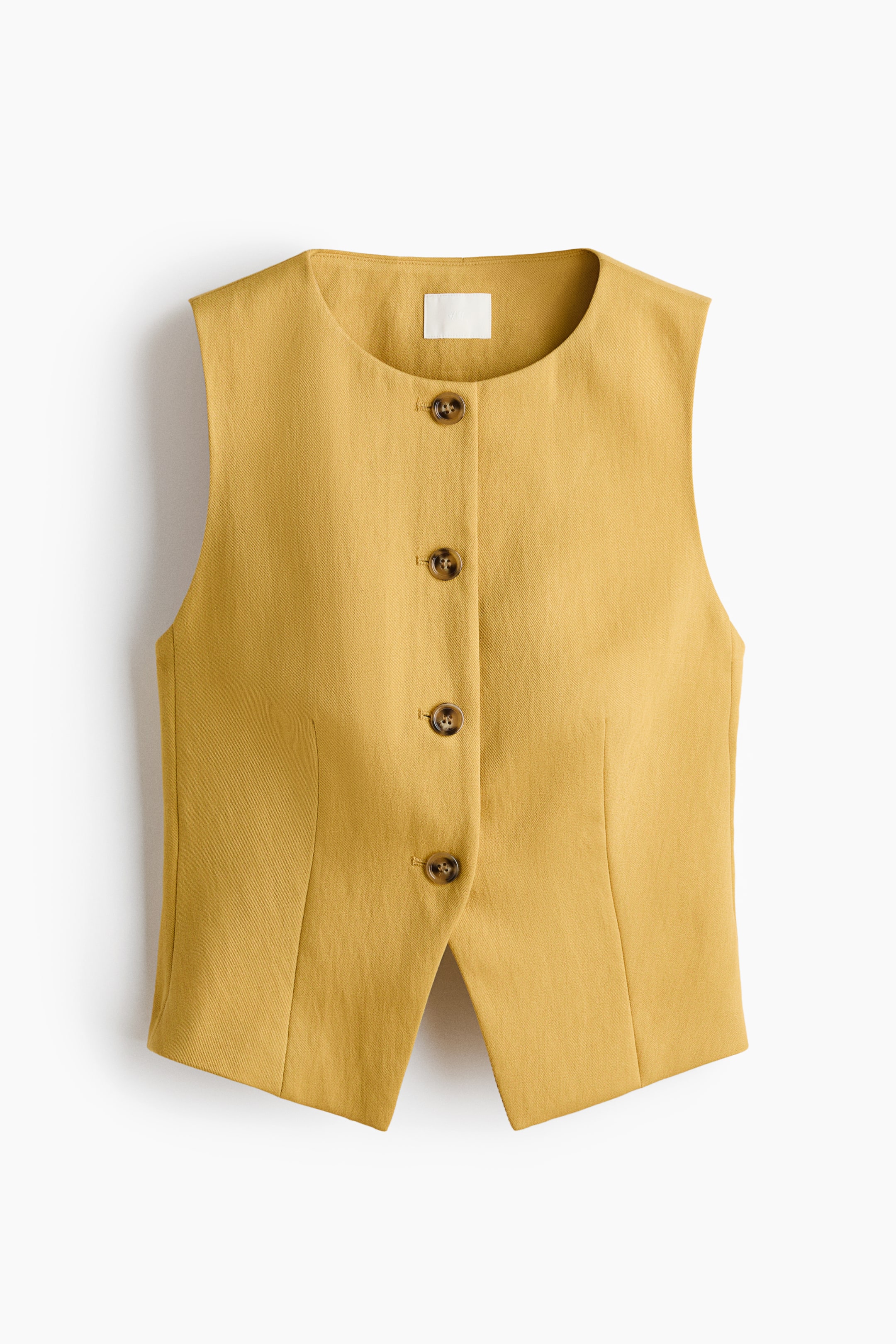 View larger image: A mustard yellow vest is displaying its FRONT, featuring a round, collarless neckline and five brown buttons down the centre. Vertical seams are shaping the front, and a V-shaped cut-out is forming the bottom hem.