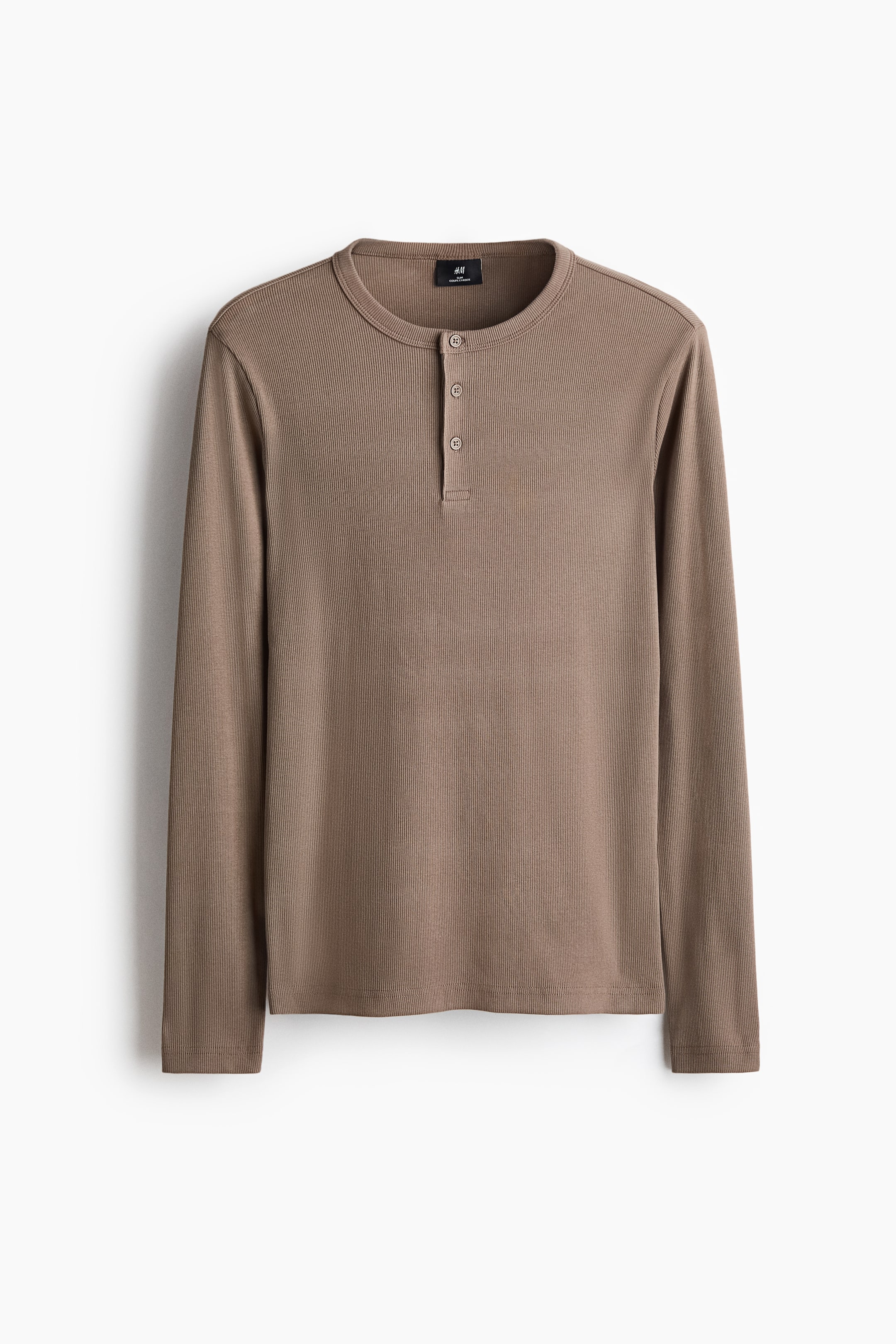 Visualizza immagine più grande: Una maglia Henley a maniche lunghe color taupe è esposta in piano, rivolta frontalmente, con una texture in maglia a coste e una chiusura a tre bottoni sotto lo scollo rotondo.