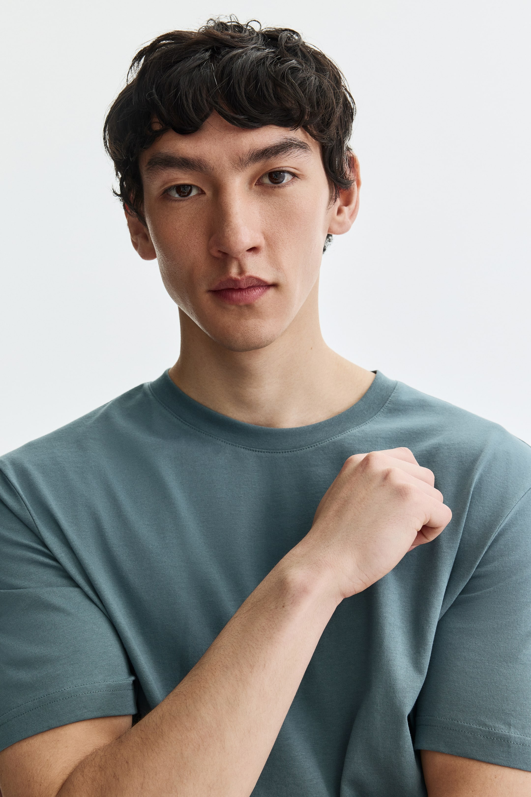 View larger image: A teal crew neck t-shirt showcasing a relaxed fit, featuring short sleeves and a smooth, plain knit texture. The visible stitching details accentuate the neckline and sleeve hems.