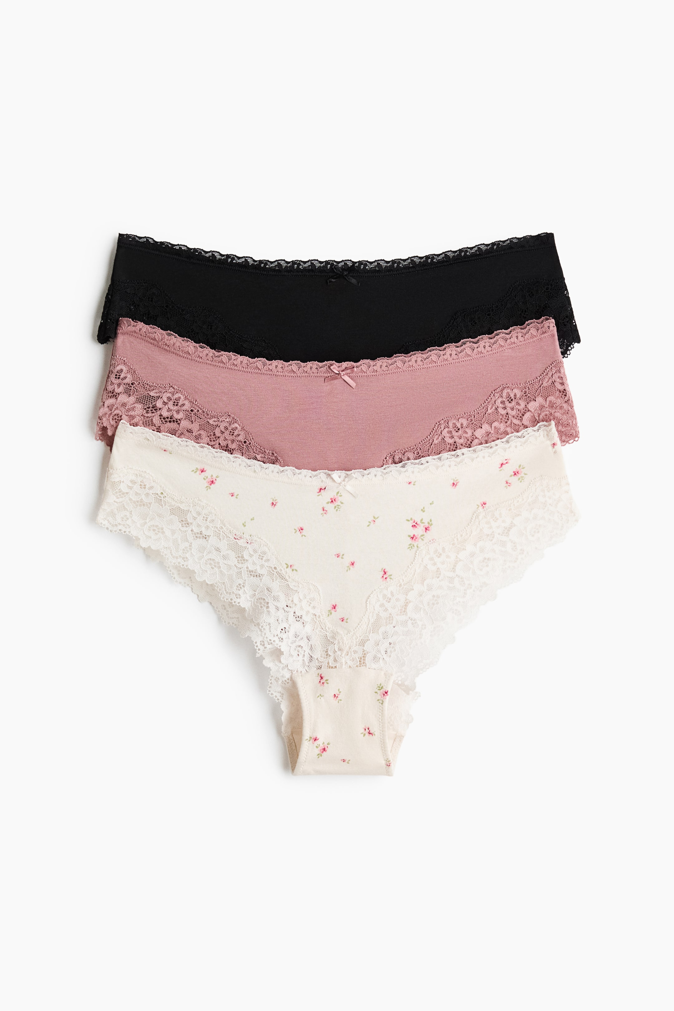 View larger image: Three briefs in cotton jersey and lace with a mid-waist design are stacked and facing forward. The top brief is black, the middle is dusty rose, and the bottom is cream with a small pink floral print, all featuring lace trim along the waist and leg openings and a small bow at the center front.