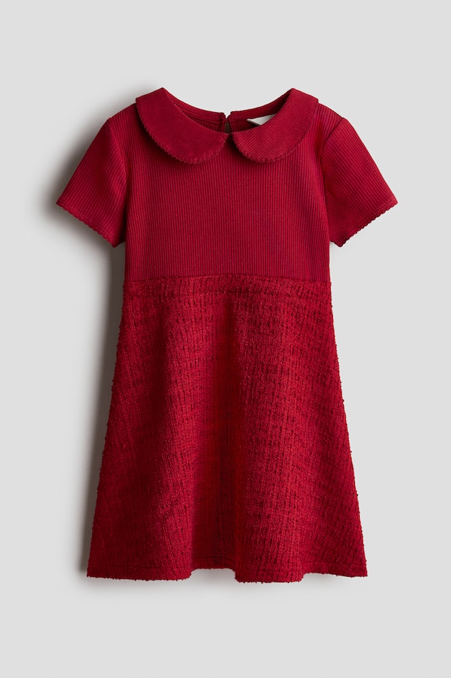 Se muestra de frente un vestido rojo con falda evasÃ© y cuello, que presenta un cuerpo de tejido de punto acanalado con cuello redondo tipo Peter Pan y mangas cortas. Este cuerpo se une a una falda evasÃ© tejida con textura, que cae en lÃ­nea recta hacia abajo. - 1