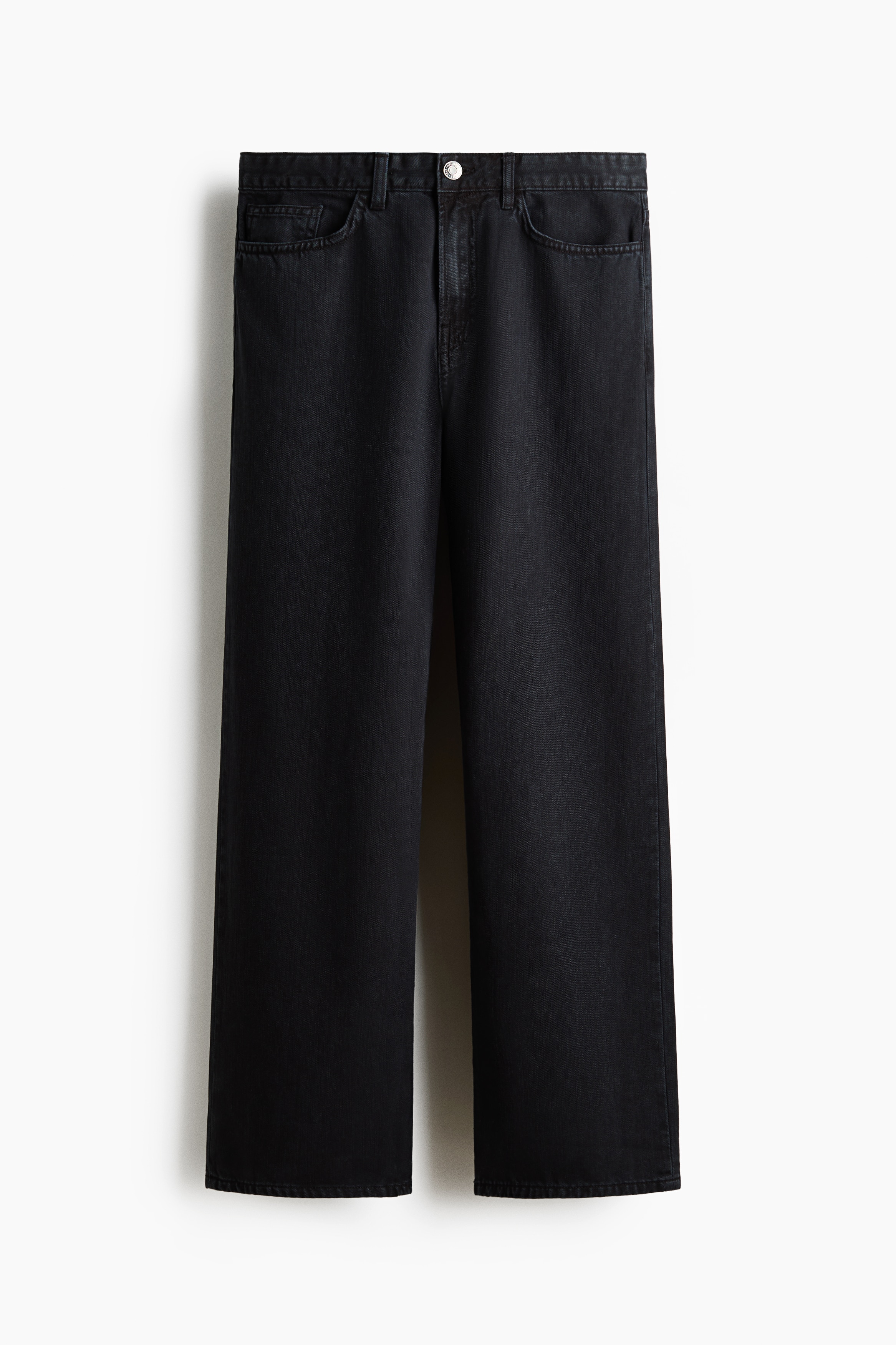 Dark cotton twill 5-pocket pants in a relaxed fit with straight legs are worn by the model, who is standing with one hand in a front pocket. The pants are styled with a blue and black plaid hooded shirt and black chunky shoes.
