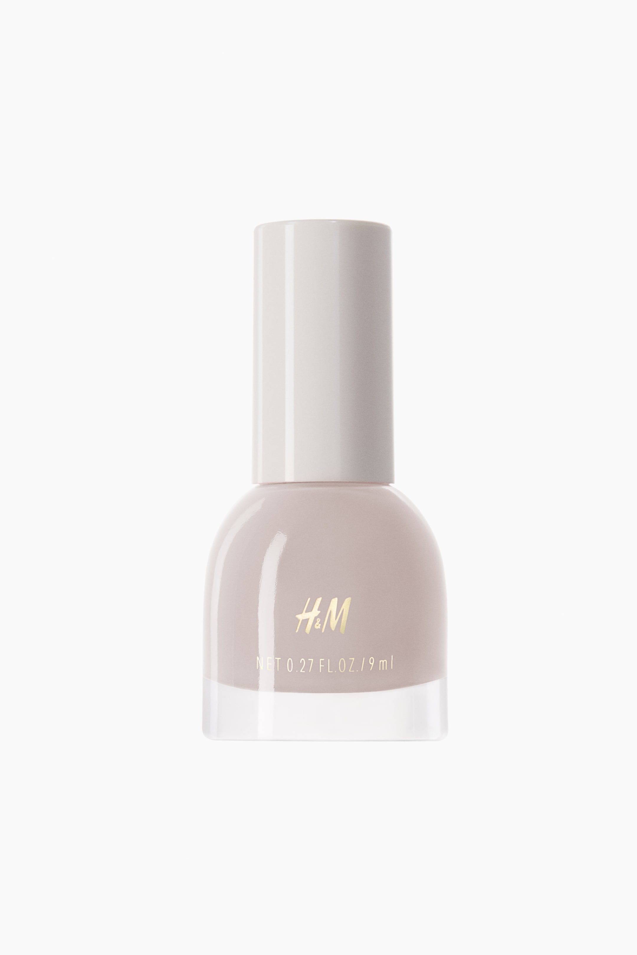 View larger image: The nail polish is contained in a transparent glass bottle with a rounded top and a clear base, facing forward. The polish is a light beige shade, topped with a cylindrical cap in a light off-white hue. The front of the bottle displays the gold H&M branding along with volume details.