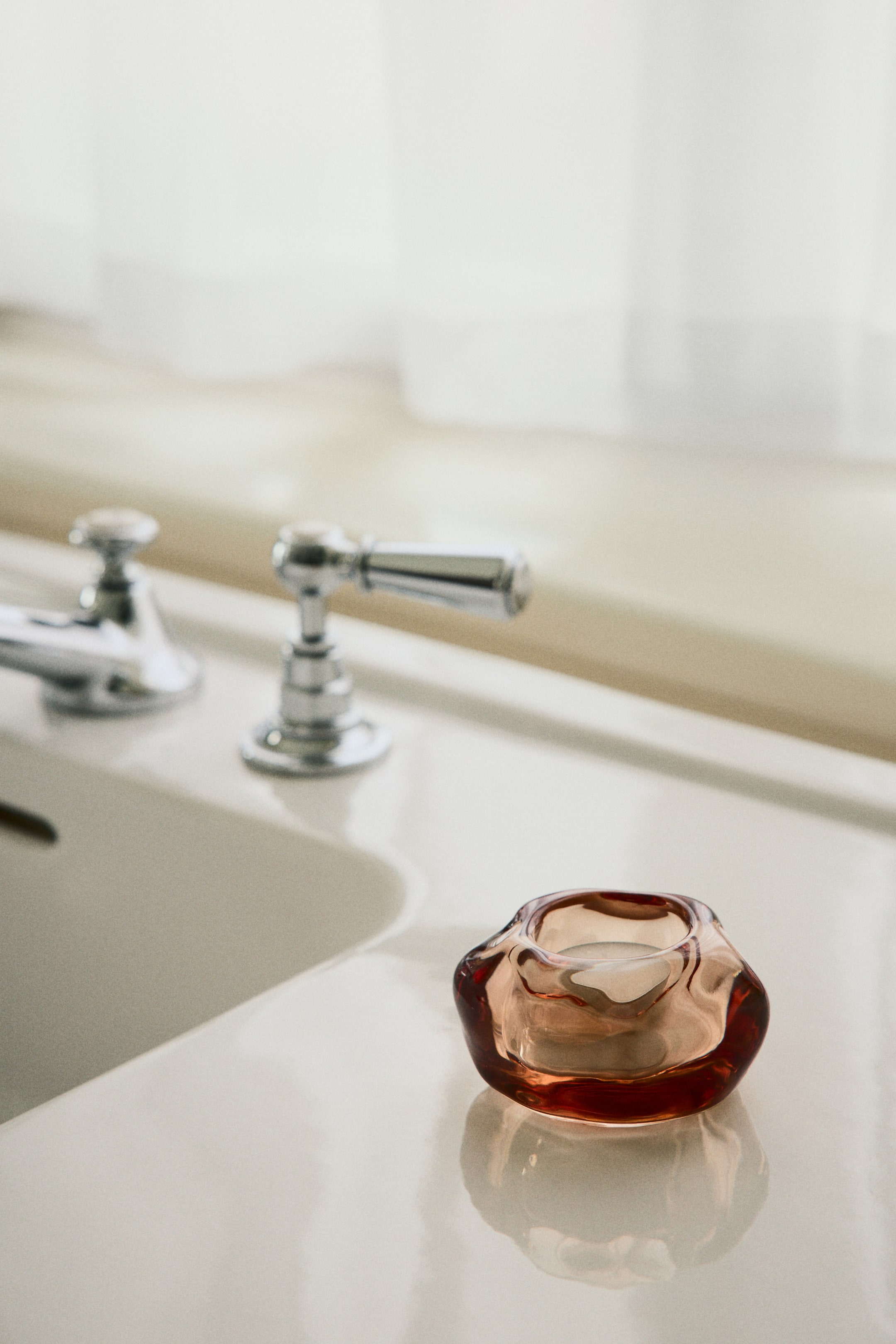 Voir une image plus grande: Un porte-bougie chauffe-plat en verre ambré translucide, de forme irrégulière, est présenté sous un léger angle, posé sur une surface de couleur claire, et contenant une bougie chauffe-plat blanche à l'intérieur.