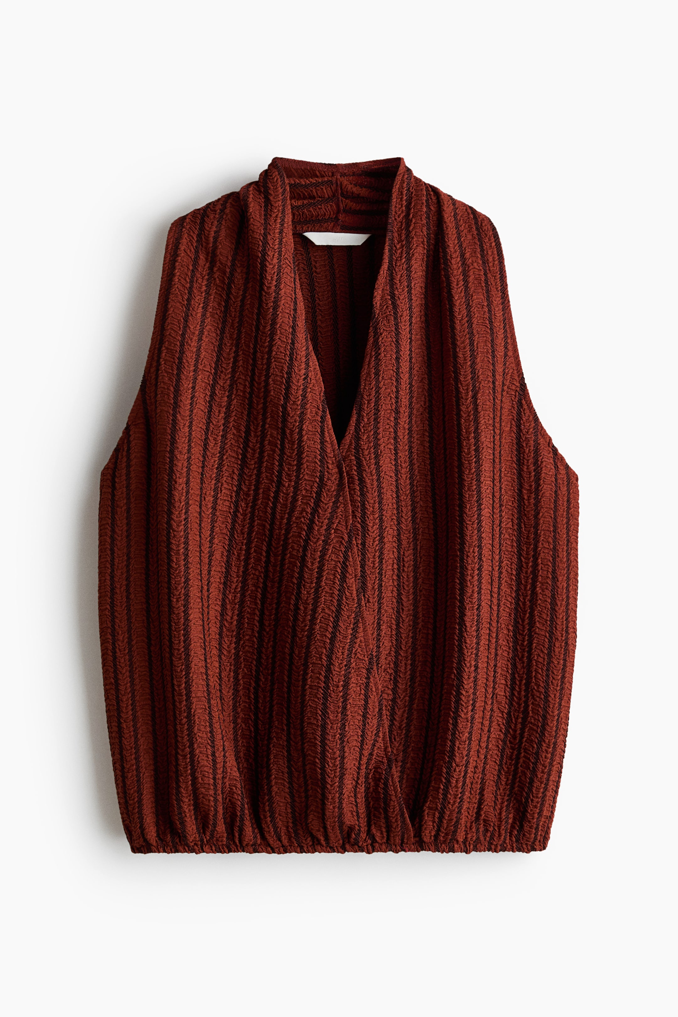 View larger image: The sleeveless top features a front-facing design in a rust-coloured crinkled fabric with dark vertical stripes. It presents a deep V-neckline in a wrap-front style, and its bottom hem is gathered and elasticated.