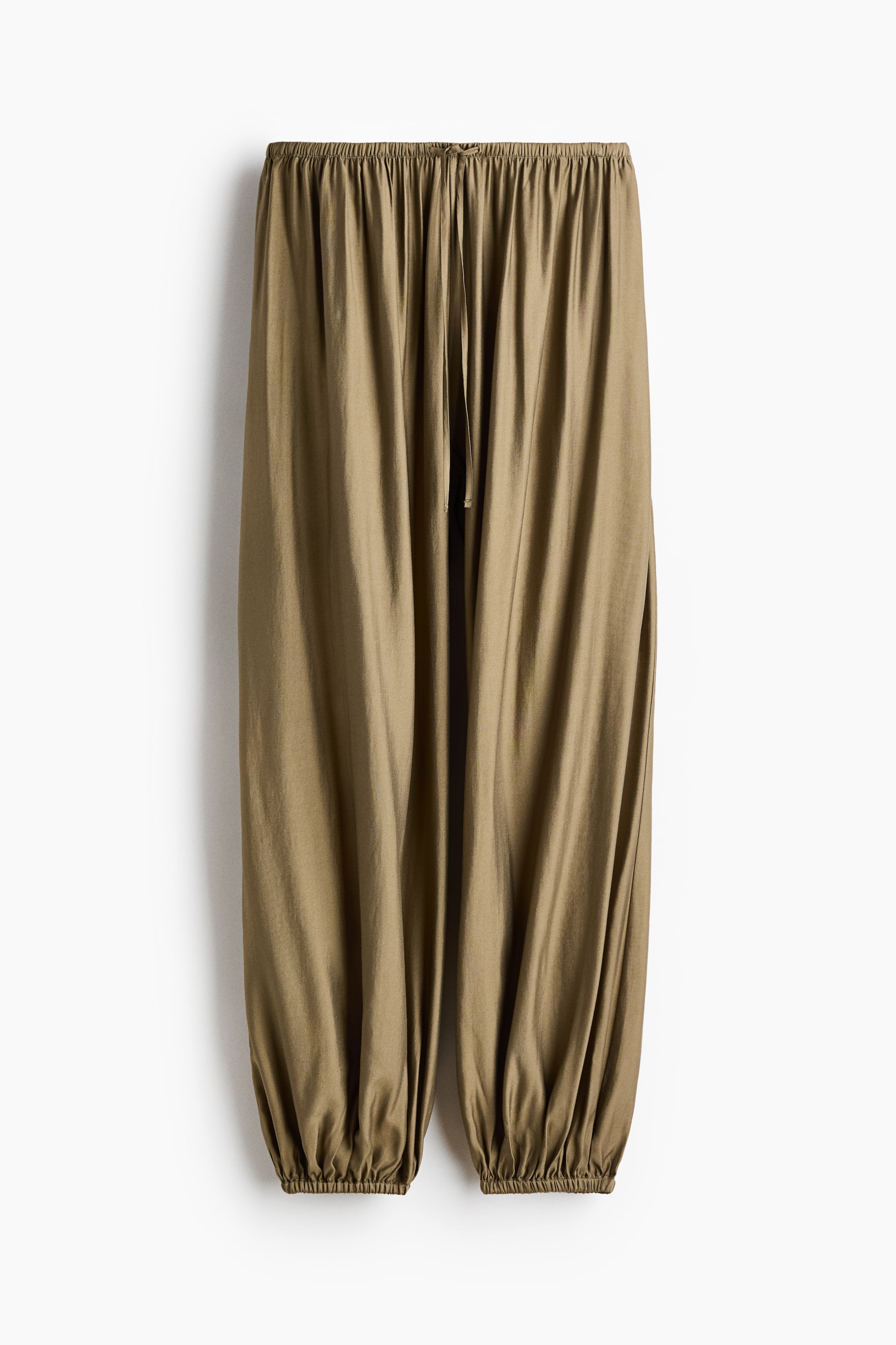 View larger image: The trousers are showcased from the front, revealing a relaxed, full silhouette in a subdued olive hue. They boast an elasticated drawstring waistband and gathered elastic cuffs at the ankles.