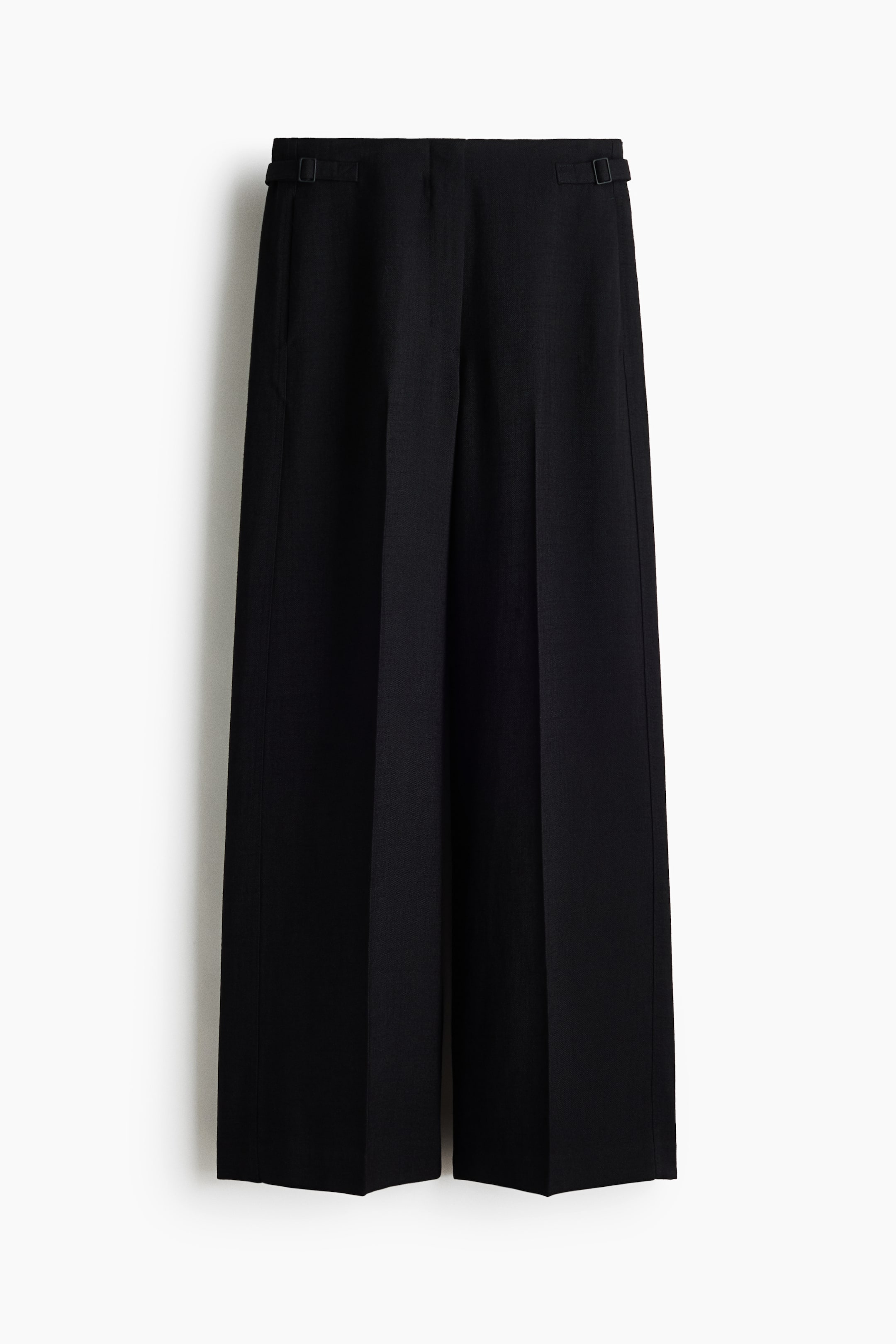 View larger image: Black trousers are showcased front-facing, featuring a waistband with adjustable side tabs and buckles. Side seam pockets are visible, and the wide-leg cut displays prominent vertical creases running down the front to a straight hem.