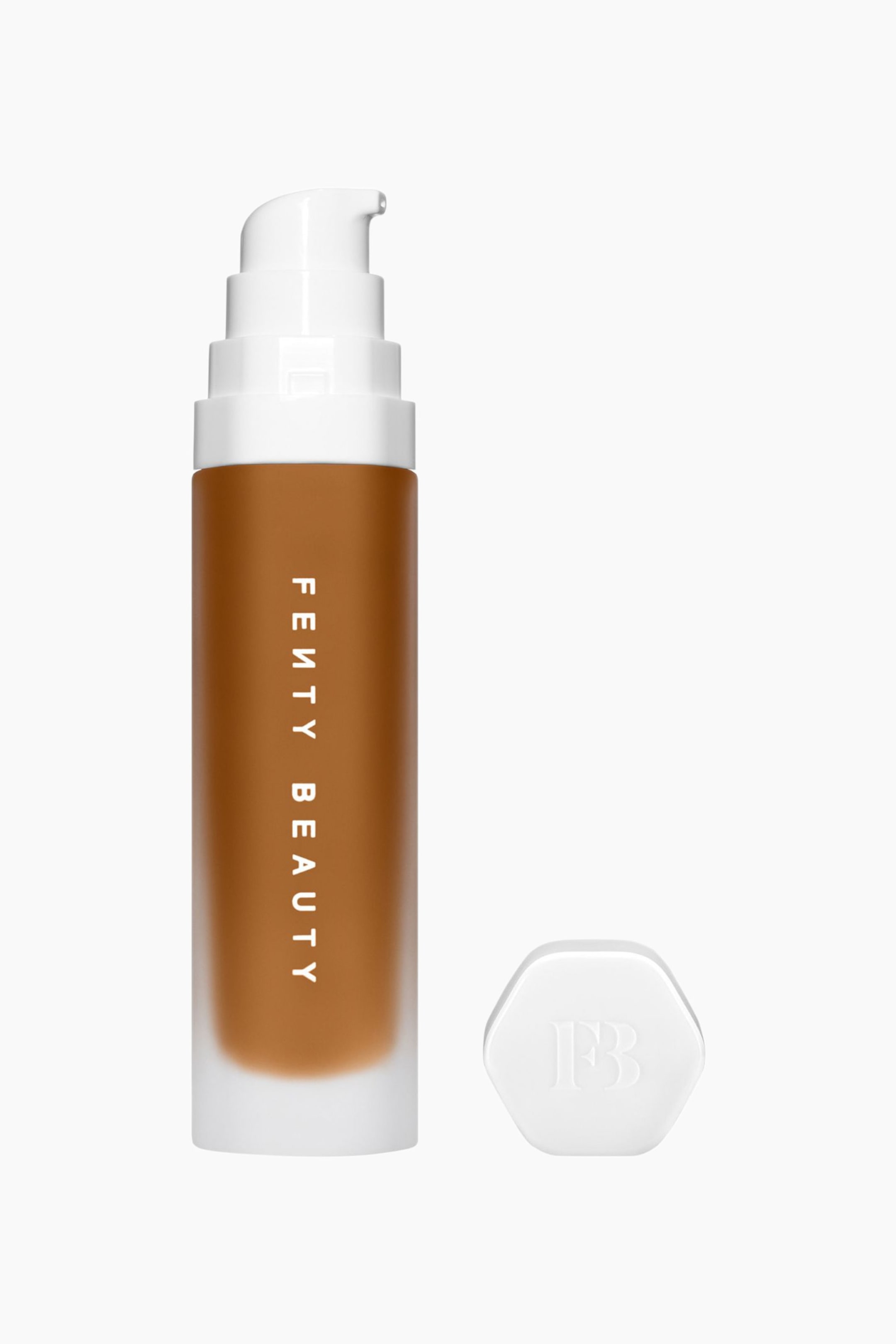 Visa större bild: Soft'lit Naturally Luminous Longwear Foundation står upprätt och visar upp en frostig cylindrisk flaska fylld med en medium till djupbrun flytande foundation, med vertikal vit ”FENTY BEAUTY”-märkning. Flaskan är försedd med en vit, stegad pumptopp, medan ett separat vitt hexagonalt lock med präglad ”FB”-logotyp ligger bredvid.