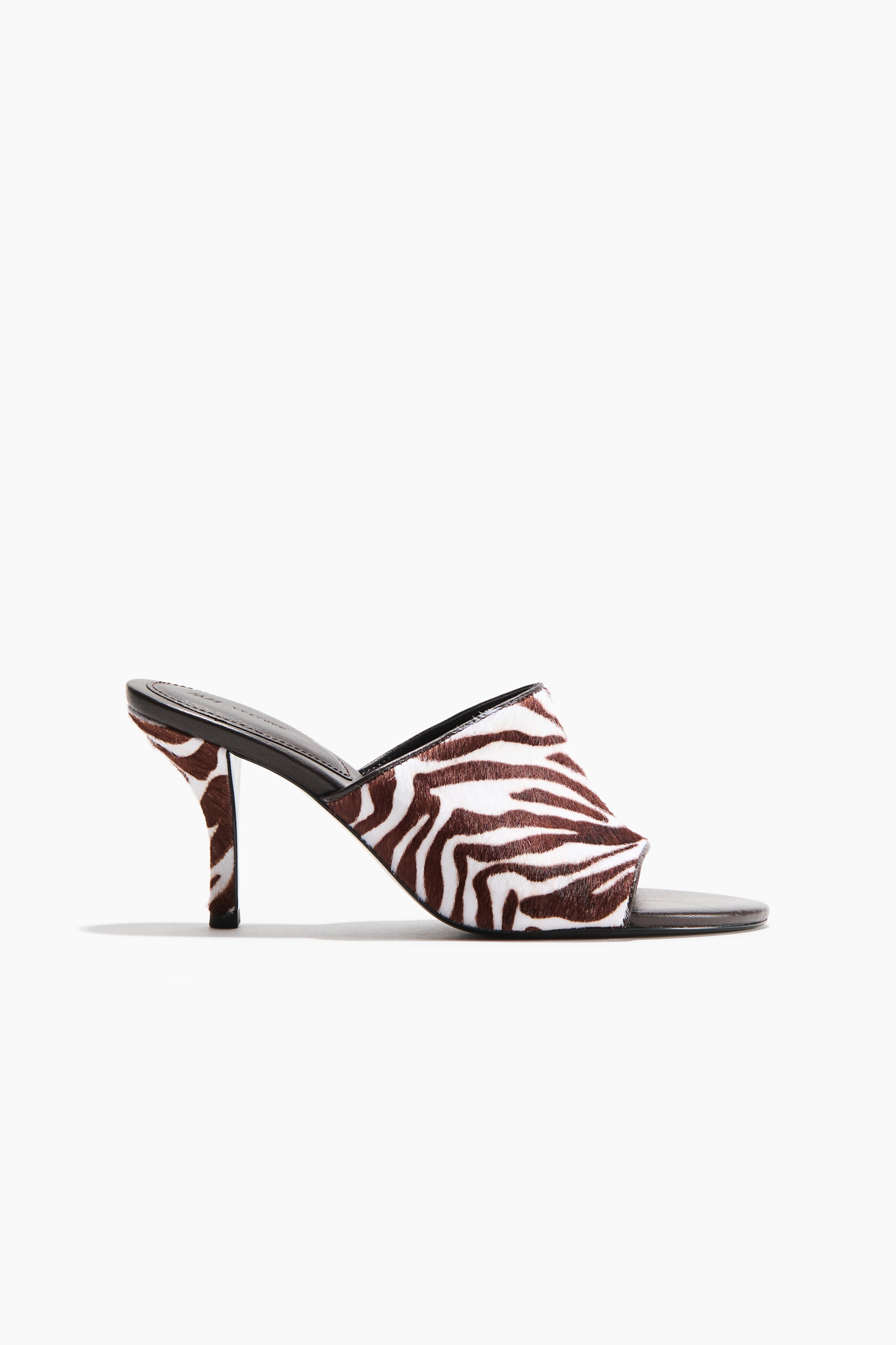 View larger image: A single sandal showcases a broad foot strap and a slender, partially enclosed heel, both adorned with a brown and white zebra print on leather. The sandal is crafted with an oblique toe.