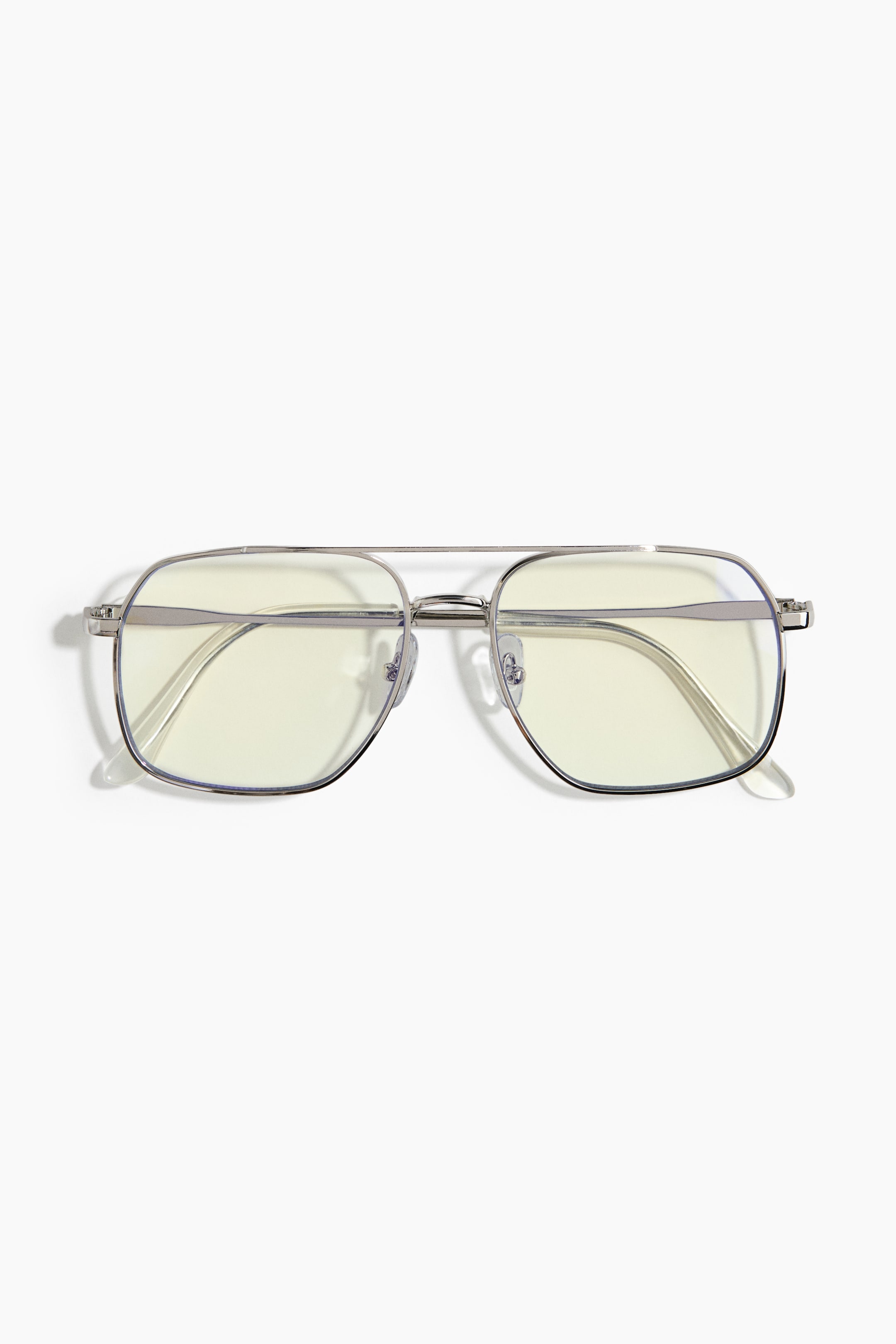 View larger image: A pair of square-shaped aviator eyeglasses is shown from the front, showcasing a thin silver metal frame with a double bridge design. The glasses feature clear lenses and slim silver temples with transparent acetate temple tips.
