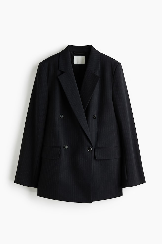 A dark pinstripe double-breasted blazer is hanging facing front, featuring wide notch lapels and a four-button front closure. The blazer is designed with long sleeves and two horizontal flap pockets at the hips. - 1